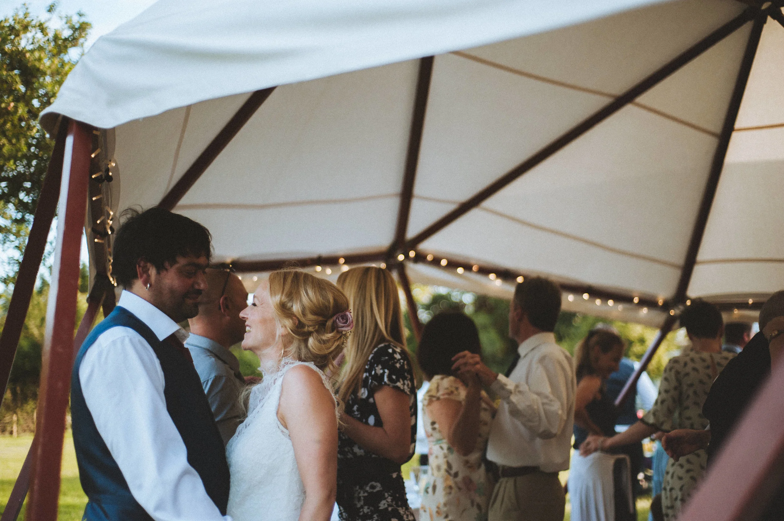 People dancing under a white canopy at an outdoor wedding reception