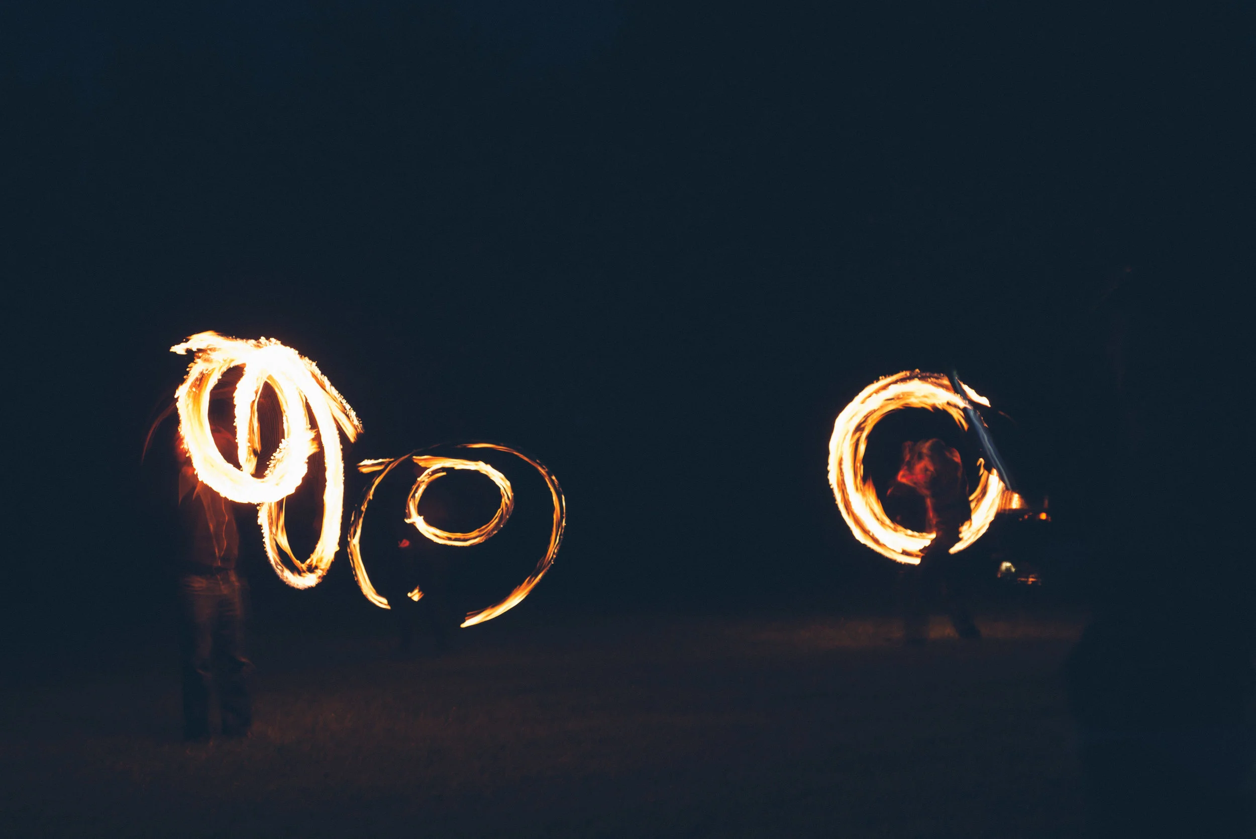 Tipi wedding captured by Cornwall wedding photographer Mark Shaw Photography People performing fire spinning or dance at night, creating circular light patterns with flaming objects.