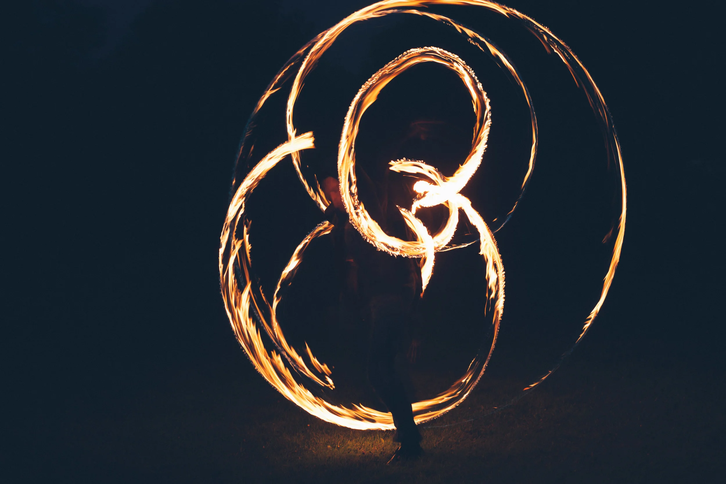 Tipi wedding captured by Cornwall wedding photographer Mark Shaw PhotographyPerformer spinning fire poi creating light trails against dark background.
