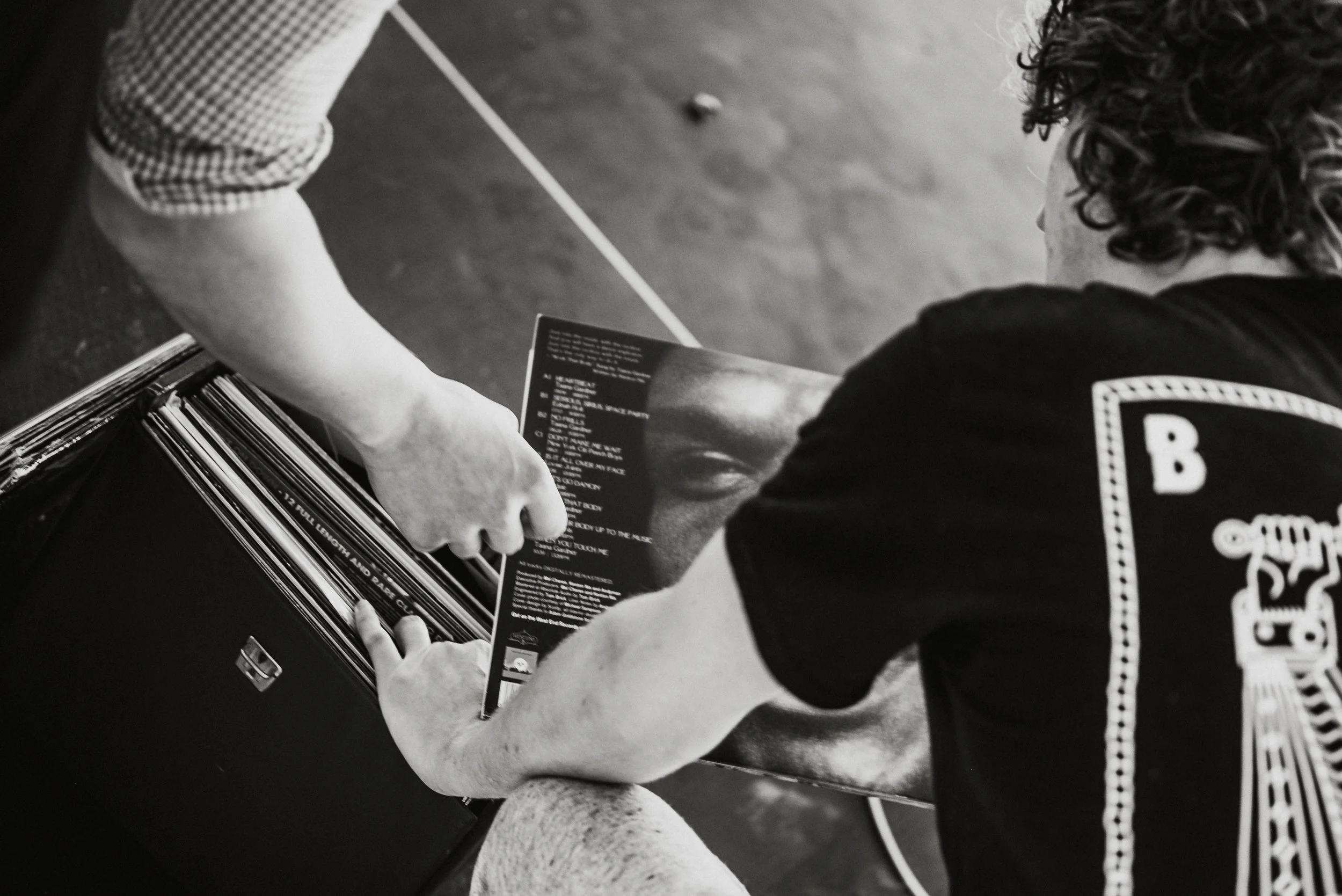 Two people browsing vinyl records, with one person holding a record that features a face.