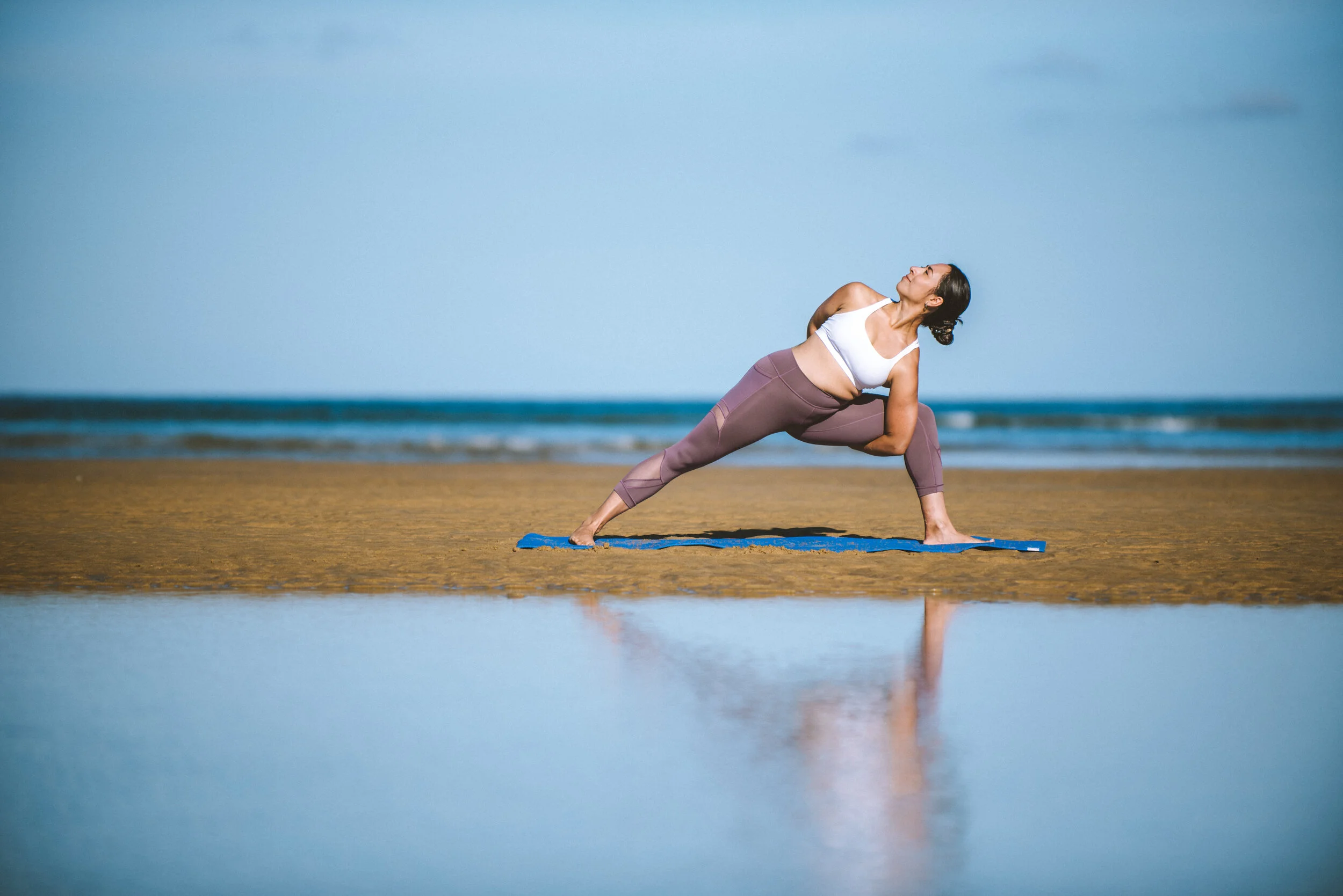 Woman practicing yoga on a beach during daylight