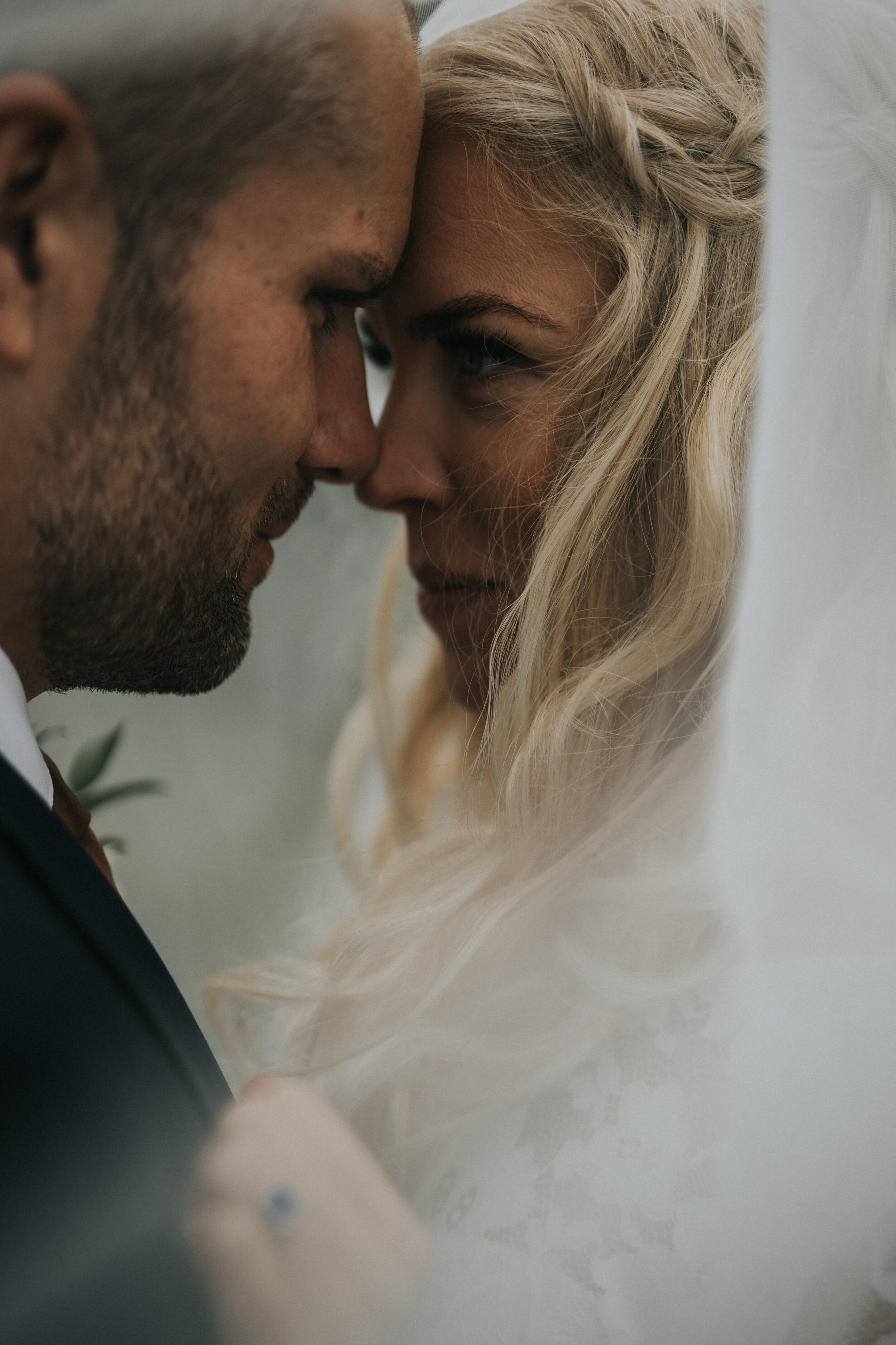 Close-up of a couple with foreheads touching, both with eyes closed, sharing an intimate moment with emotional expressions.