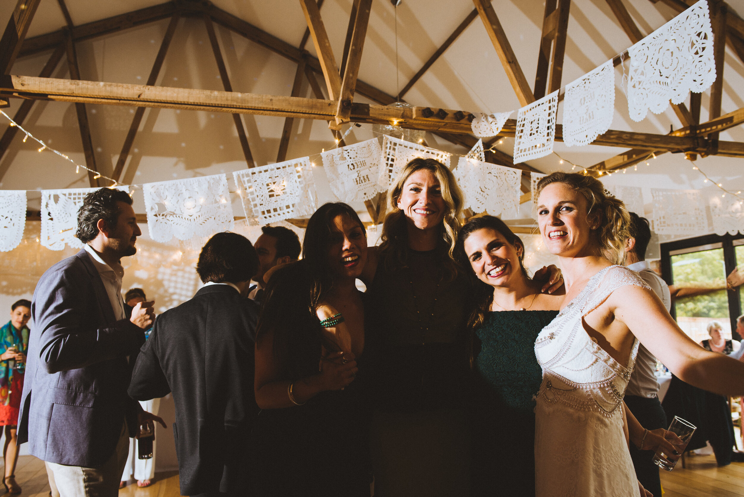 Group of women smiling and posing at a celebration or party, with festive decorations hanging from the ceiling.