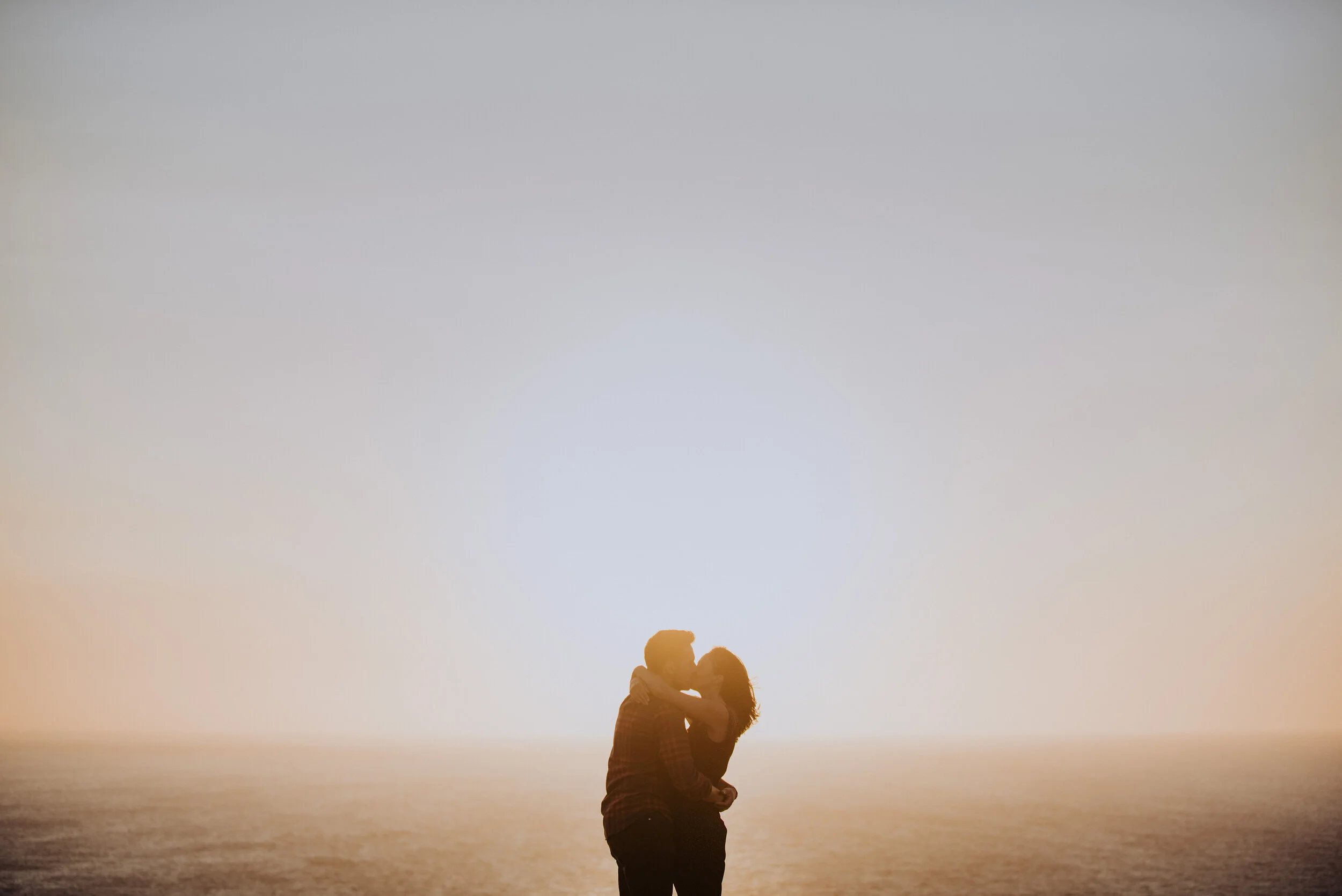 A couple kissing at sunset on the beach
