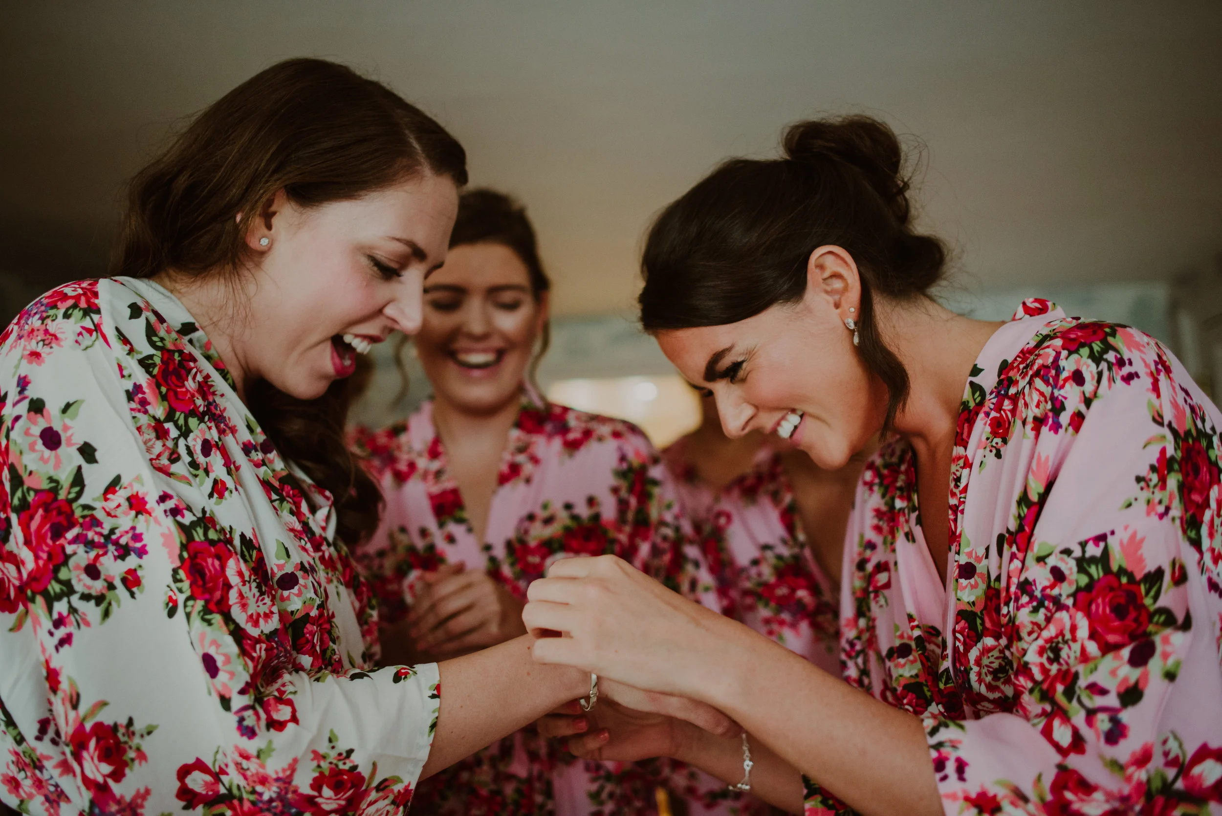 Women in floral robes exchanging rings, smiling happily.