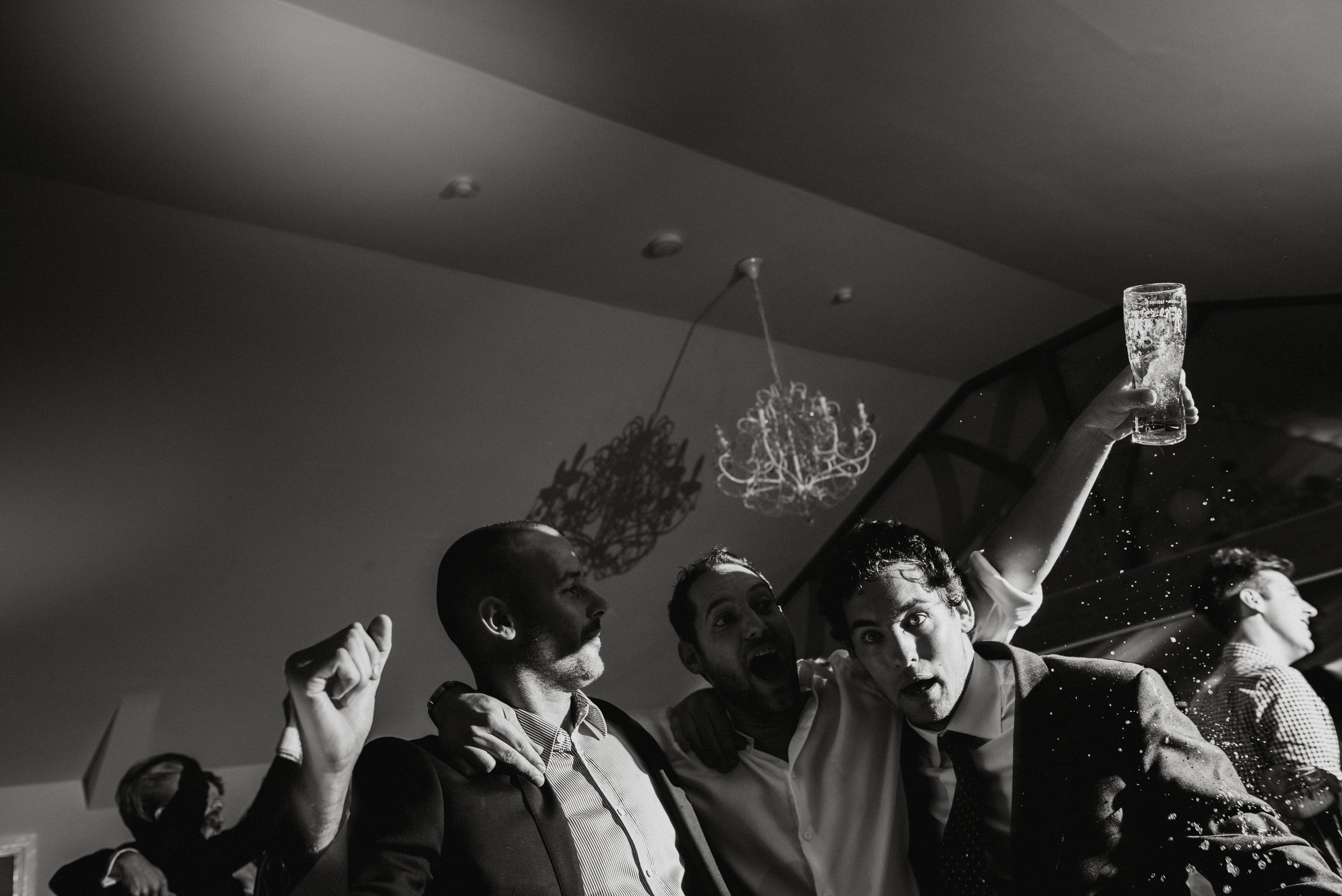 People celebrating at a party; one person holding a glass raised in the air, others smiling and enjoying the moment.