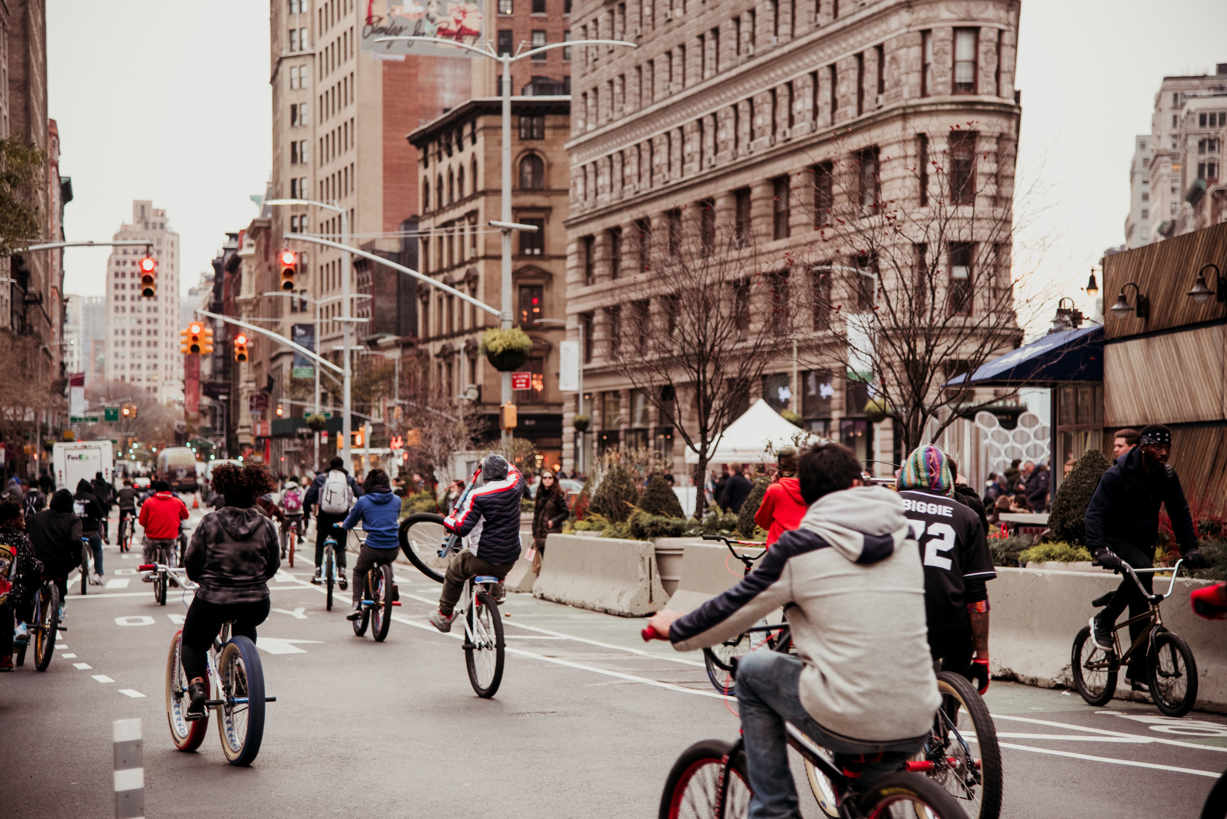 Crowd of people riding bicycles on city street with tall buildings and traffic lights