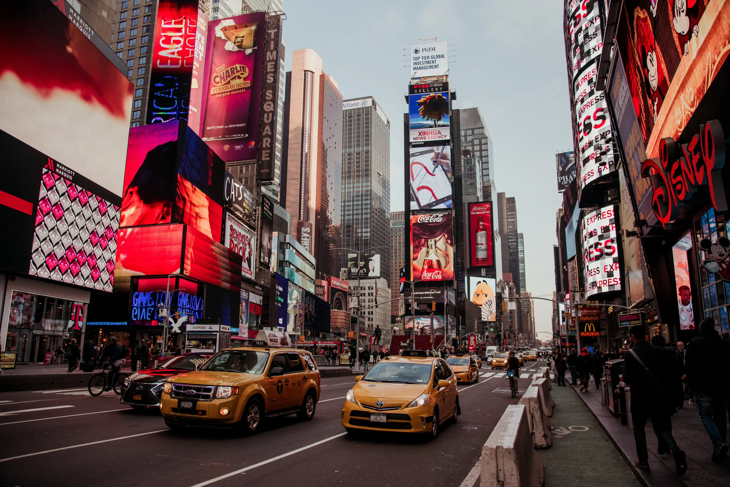 Time Square in New York City with digital billboards and yellow taxis on the street.