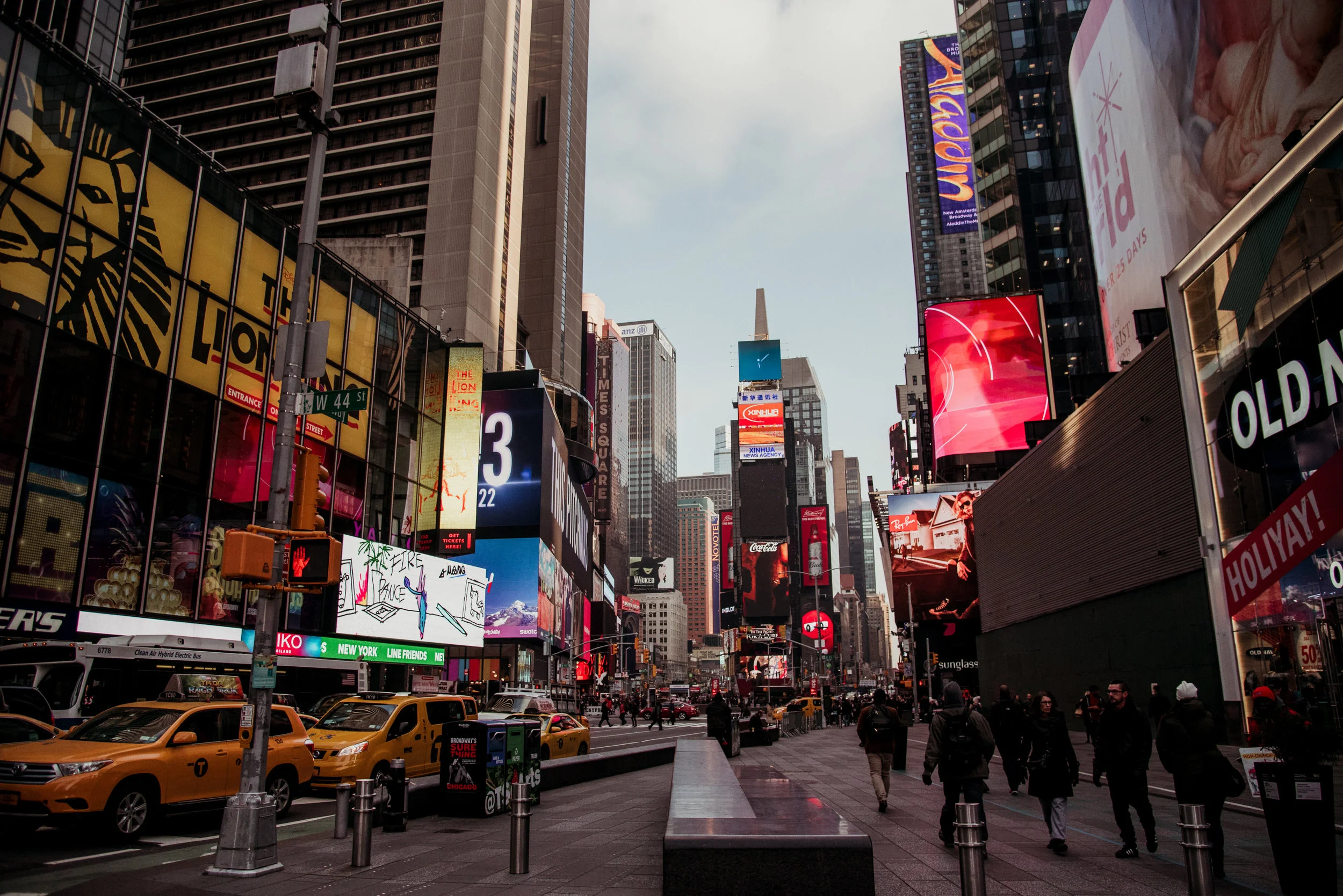 Times Square in New York City with tall buildings, digital billboards, yellow taxis, and pedestrians.