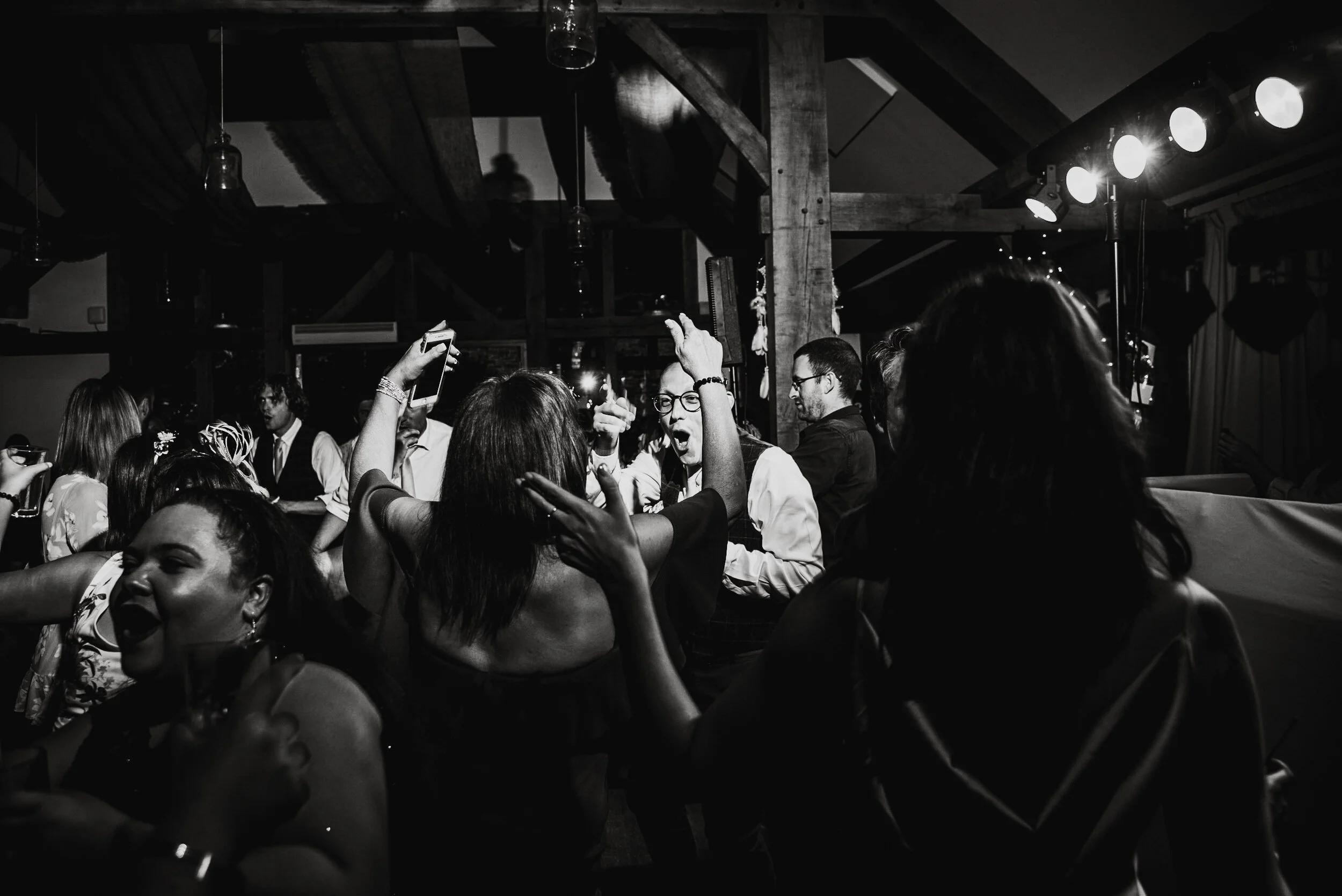 People dancing and socializing at a lively indoor party or celebration in black and white photo.