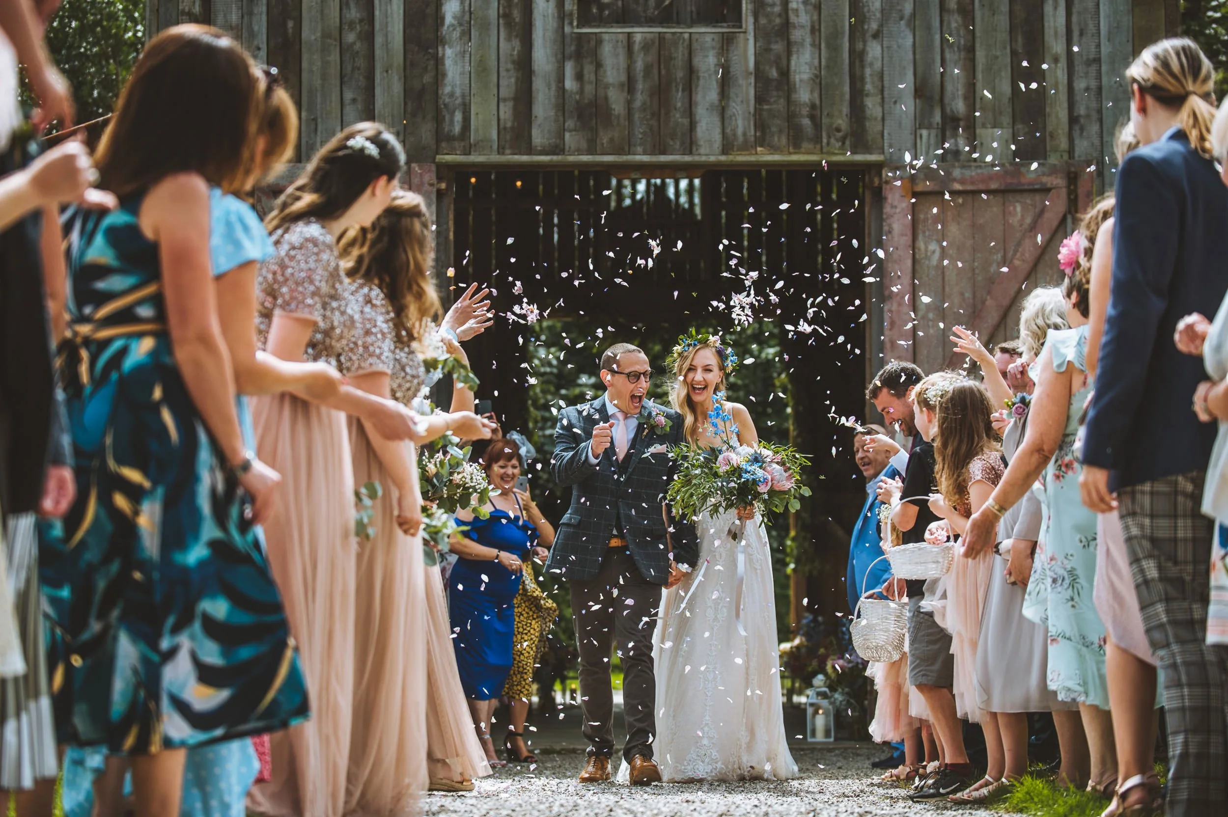 Bride and groom walk down confetti aisle at Nancarrow Farm, captured by Cornwall wedding photographer Mark Shaw Photography
