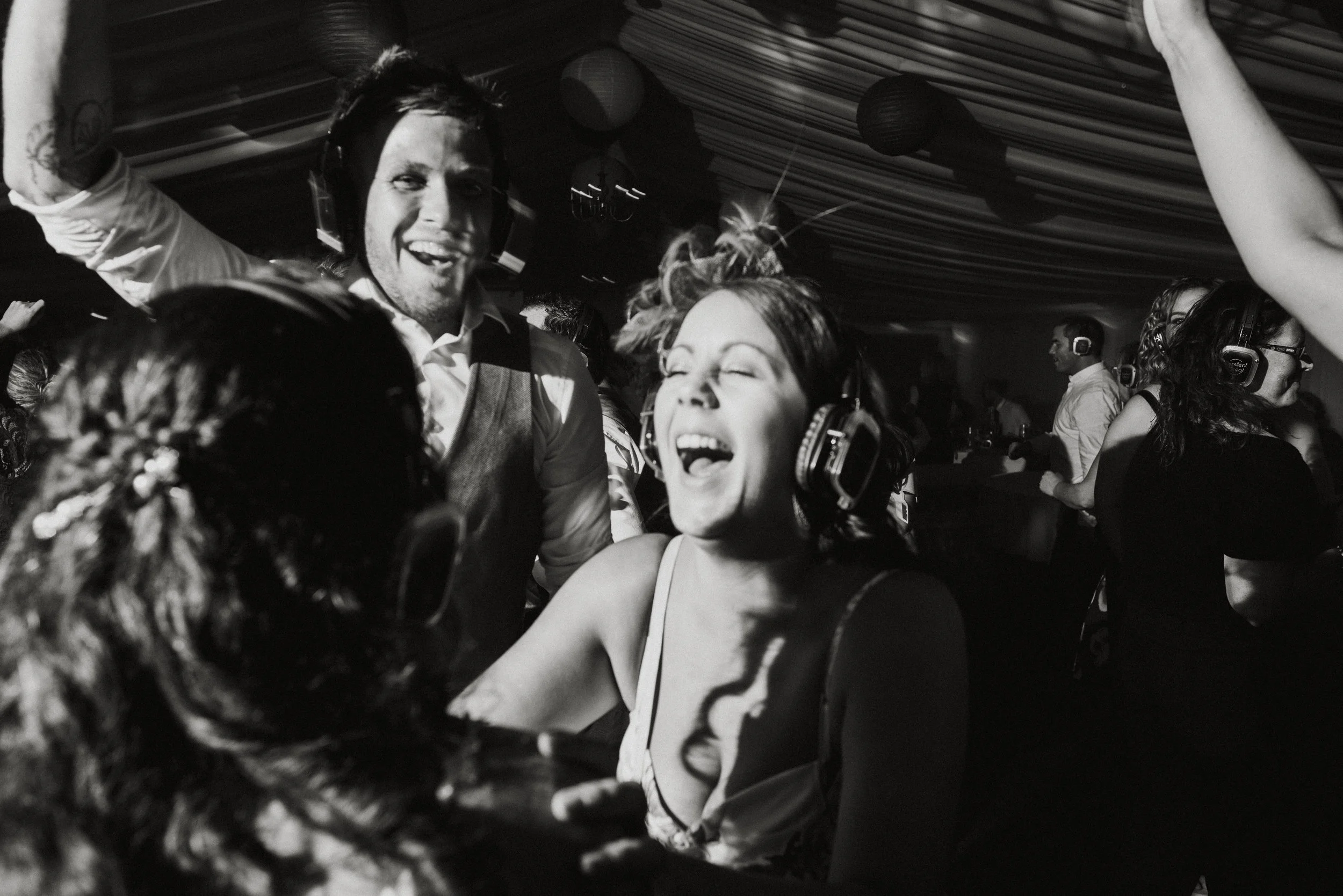 People at a party dancing and celebrating, wearing headphones and smiling.