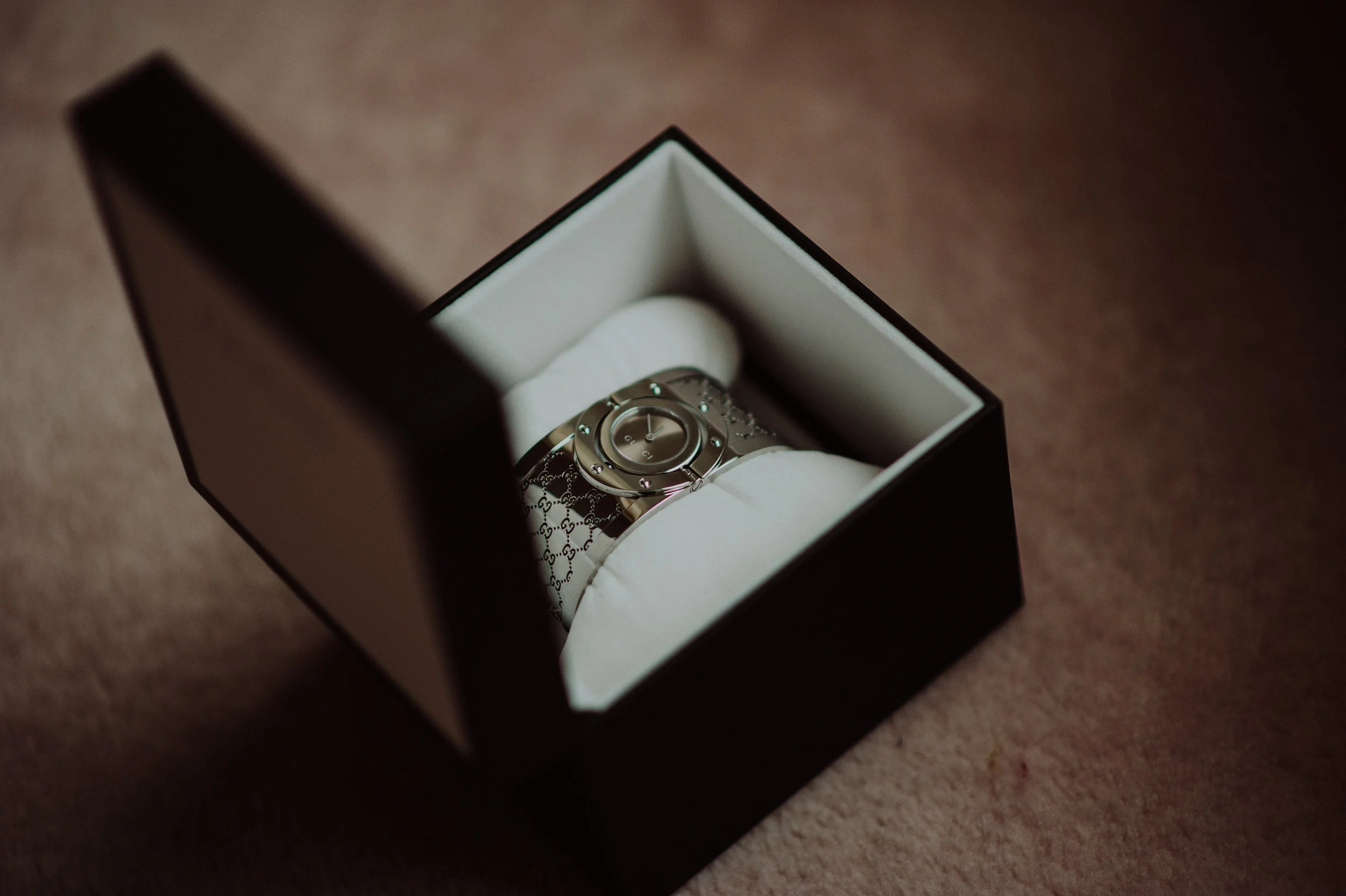 A luxury Gucci wristwatch in a black gift box, resting on a cushioned interior.