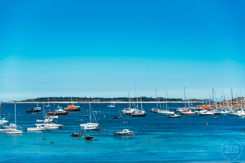 Isles of scilly photography. Marina filled with boats and sailboats on calm water, with a clear blue sky.