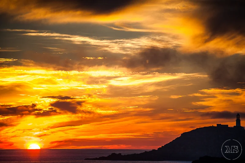 Sunset over the ocean with a partly cloudy sky and a lighthouse on a hill to the right - Isles of Scilly Professional Photographer - Mark Shaw Photography 