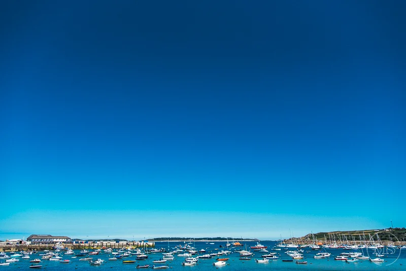 Isles of scilly photography. View of a harbor filled with sailboats and motorboats under a clear blue sky.