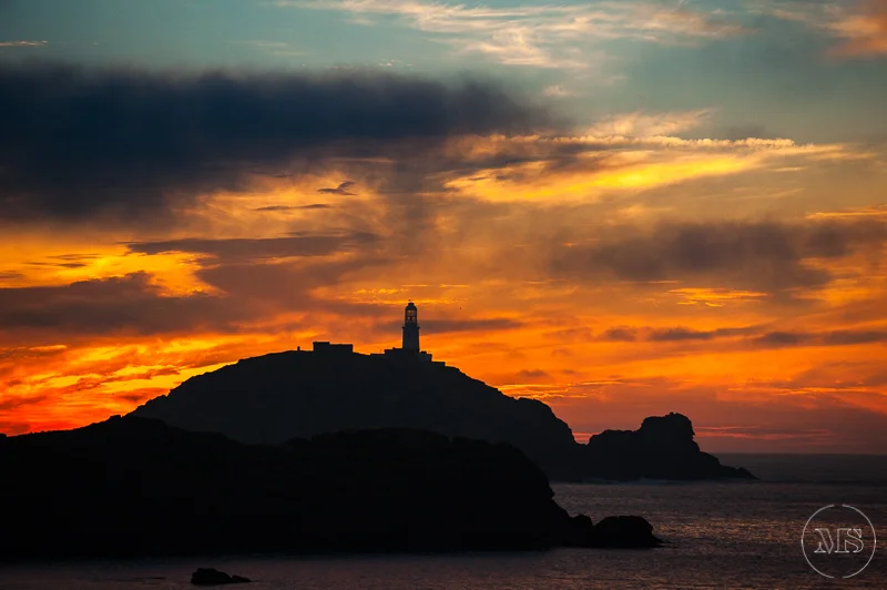 Isles of scilly photography. Sunset over a coastal hill with a lighthouse silhouette