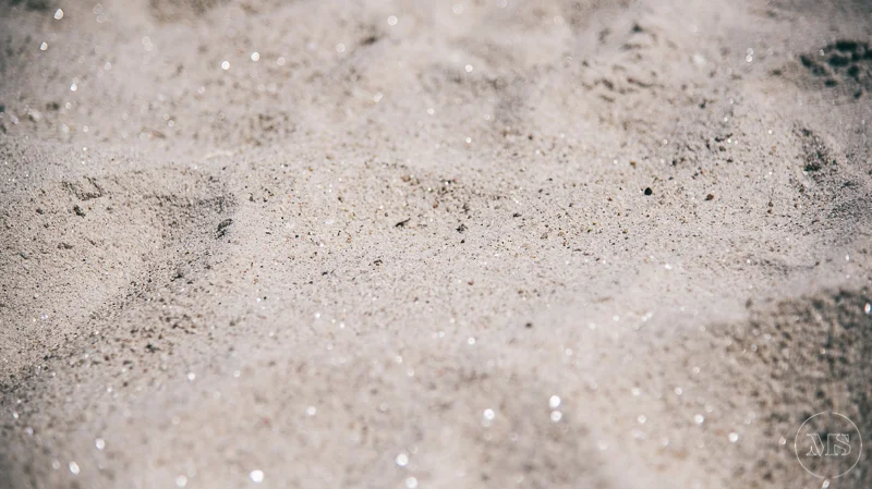 Isles of scilly photography. Close-up of sandy beach with small, reflective particles and faint footprints.
