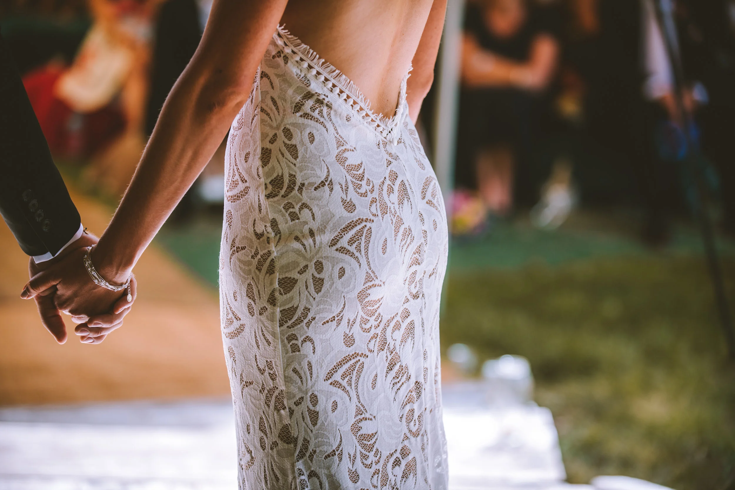 Bride and groom holding hands during wedding ceremony, close-up of bride's lace wedding dress and holding hands.