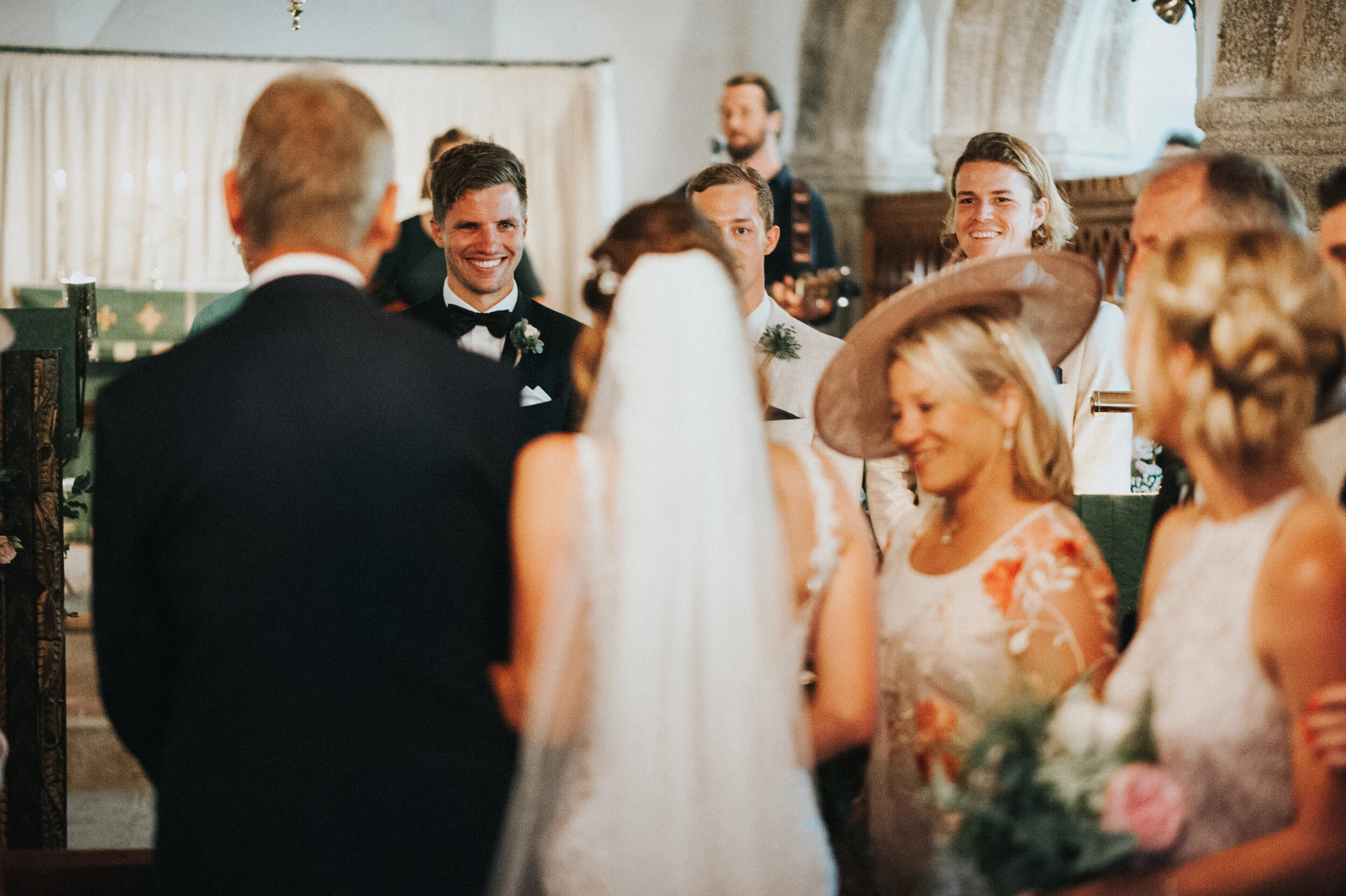 Daymer bay wedding photography in Cornwall captured by Mark Shaw Photography - A wedding ceremony with the bride, groom, and guests smiling in a church.