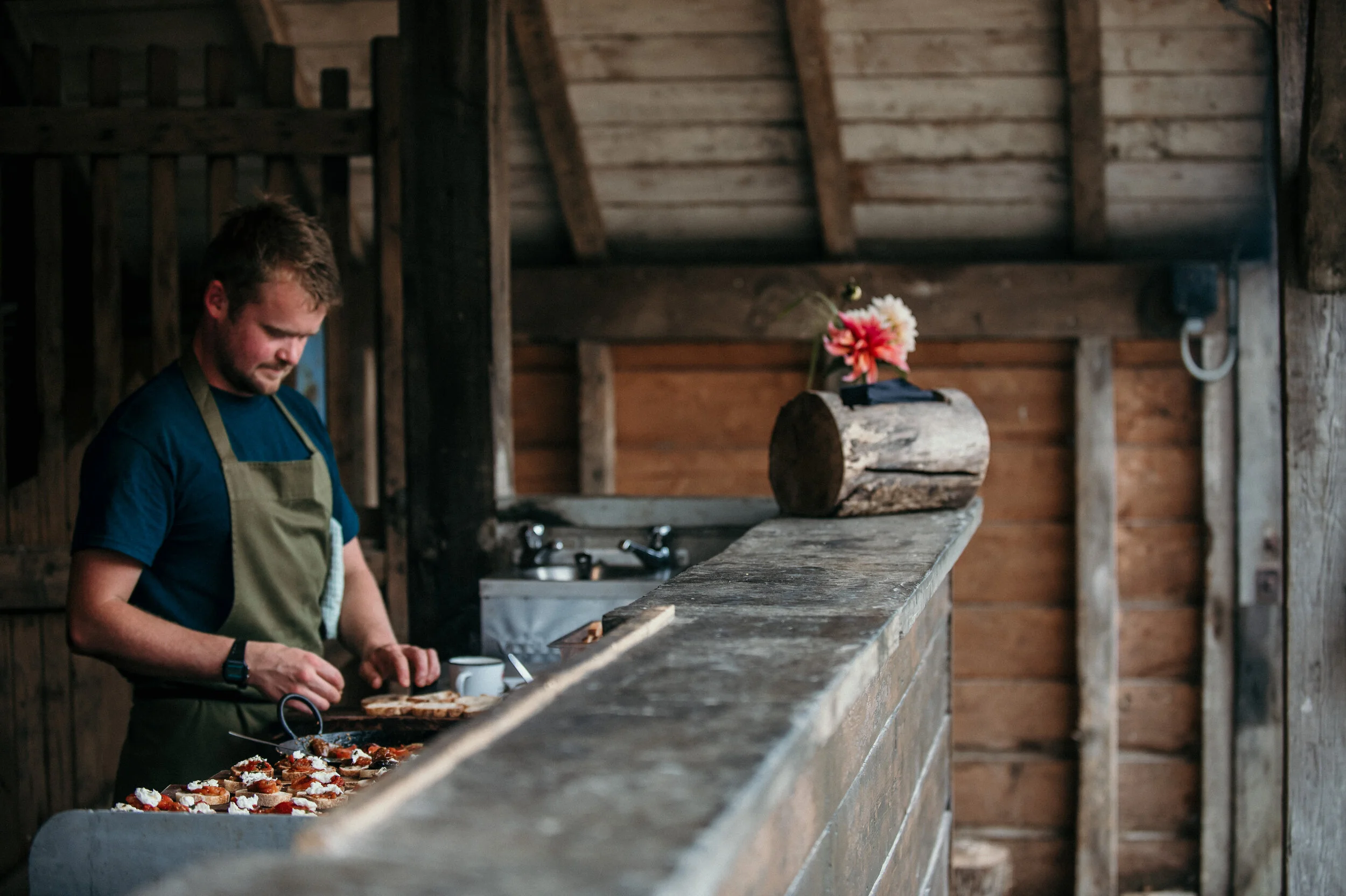Person in apron preparing food in rustic kitchen with wooden decor.