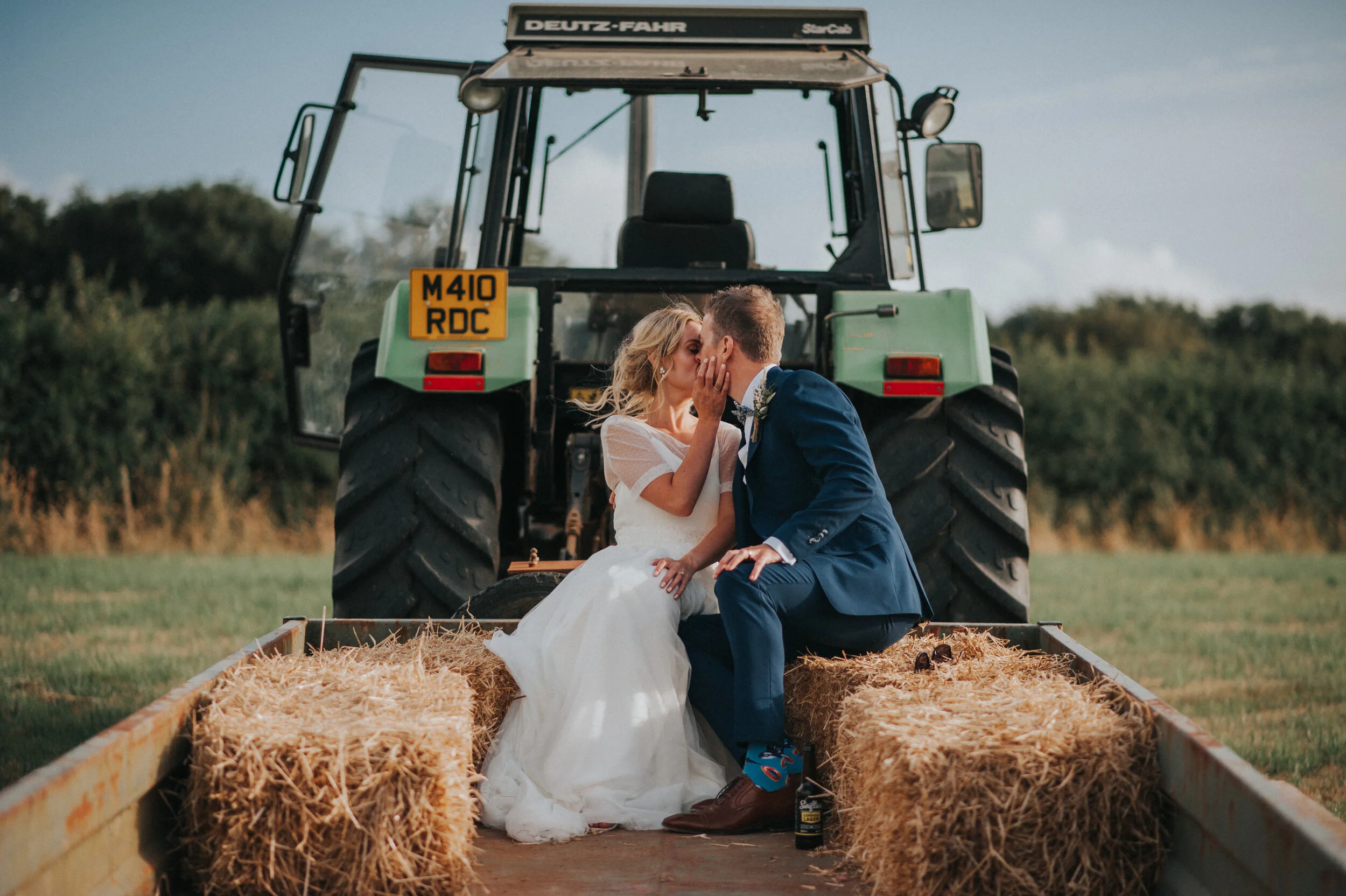 A bride and groom tractor ride at Launcells Barton in Bude, captured by Cornwall wedding photographer Mark Shaw Photography