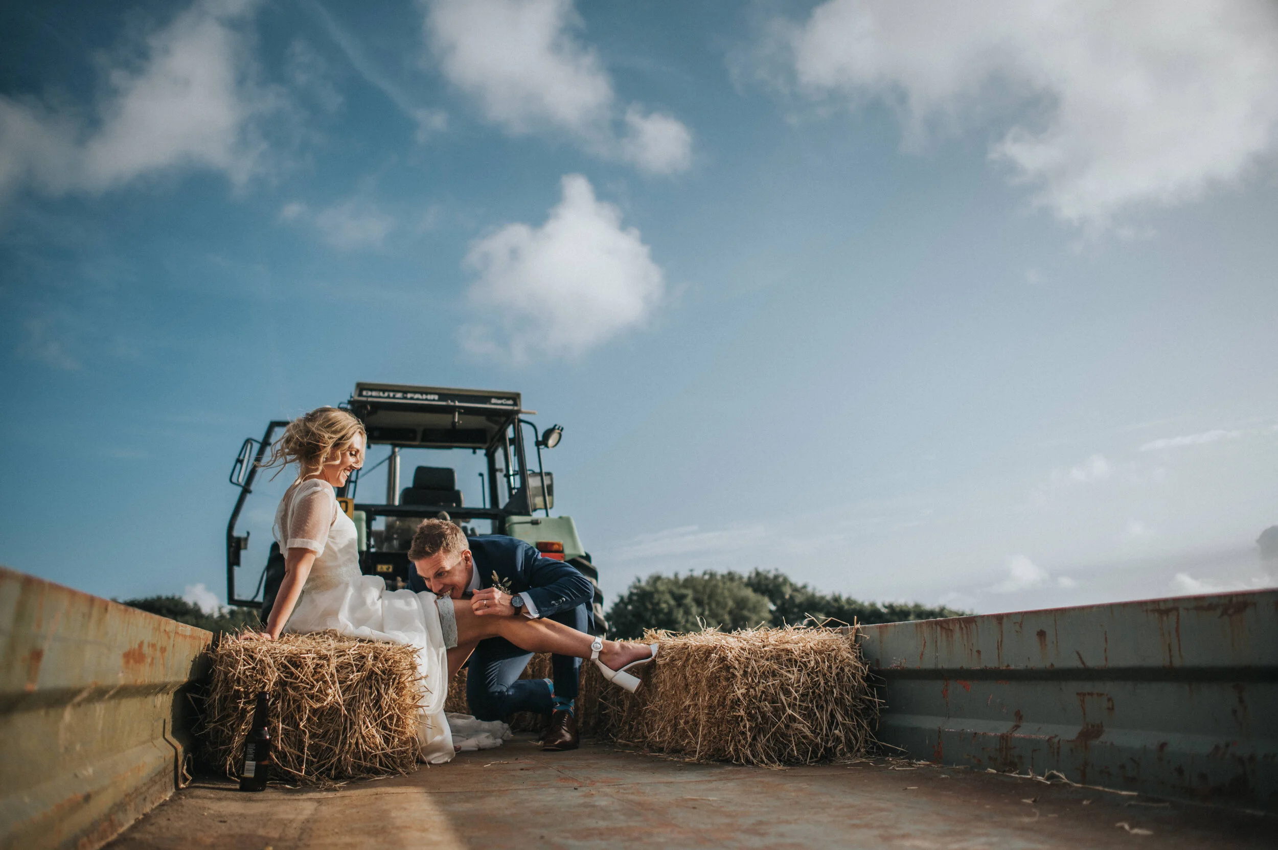 A bride and groom tractor ride at Launcells Barton in Bude, captured by Cornwall wedding photographer Mark Shaw Photography