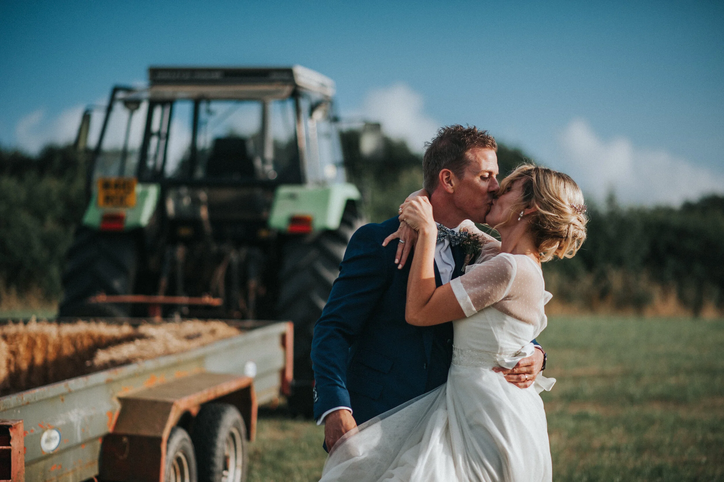 A bride and groom tractor ride at Launcells Barton in Bude, captured by Cornwall wedding photographer Mark Shaw Photography