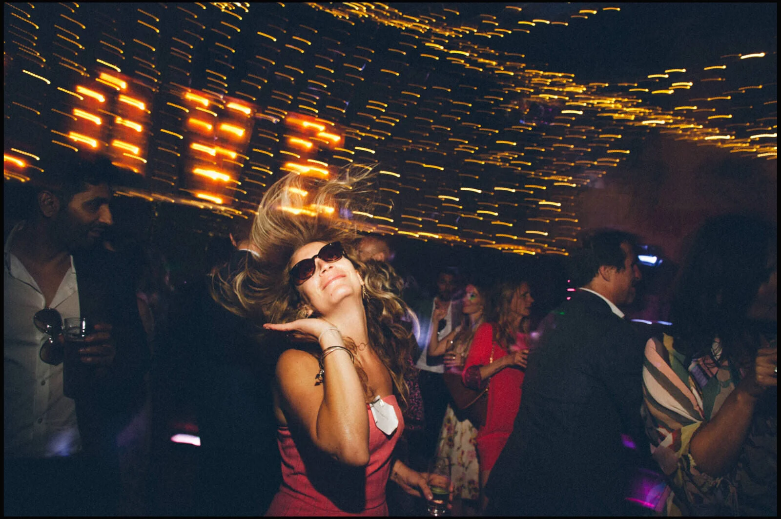 People dancing and enjoying music at a party with colorful lights and blurred motion effects.