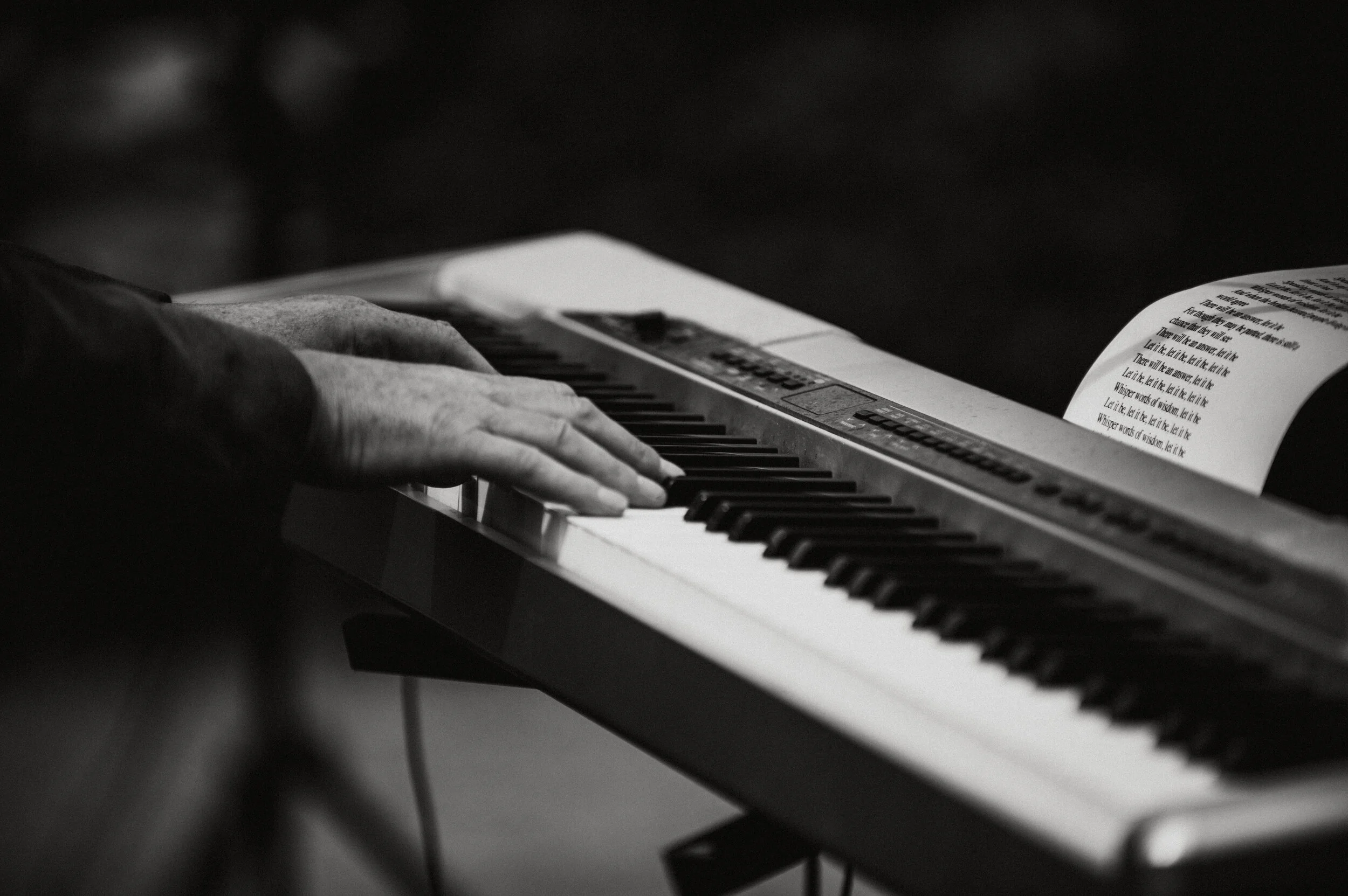 A person playing a keyboard with a sheet of music or lyrics open above the keys.