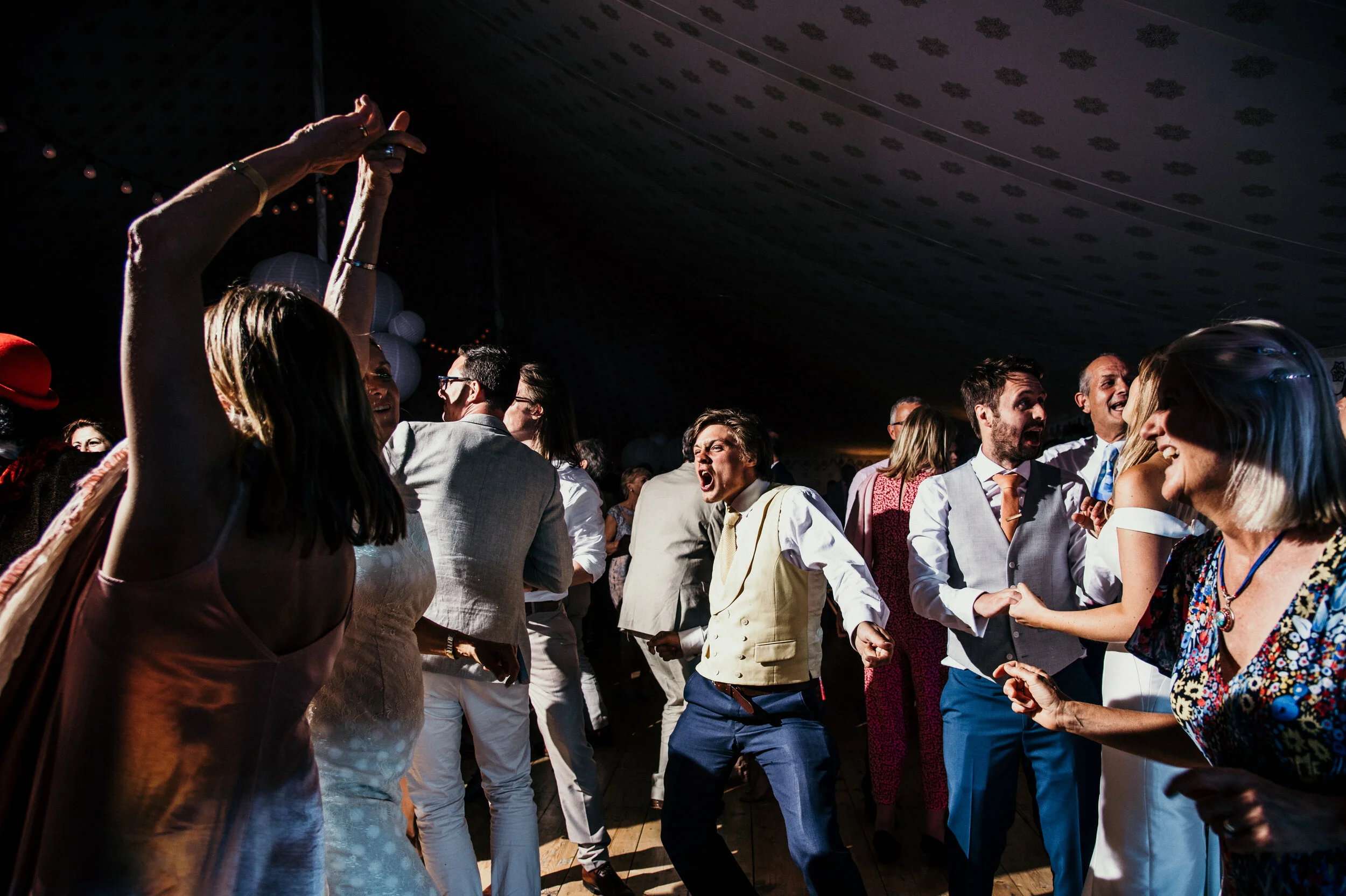People dancing and celebrating at a party or wedding reception indoors.