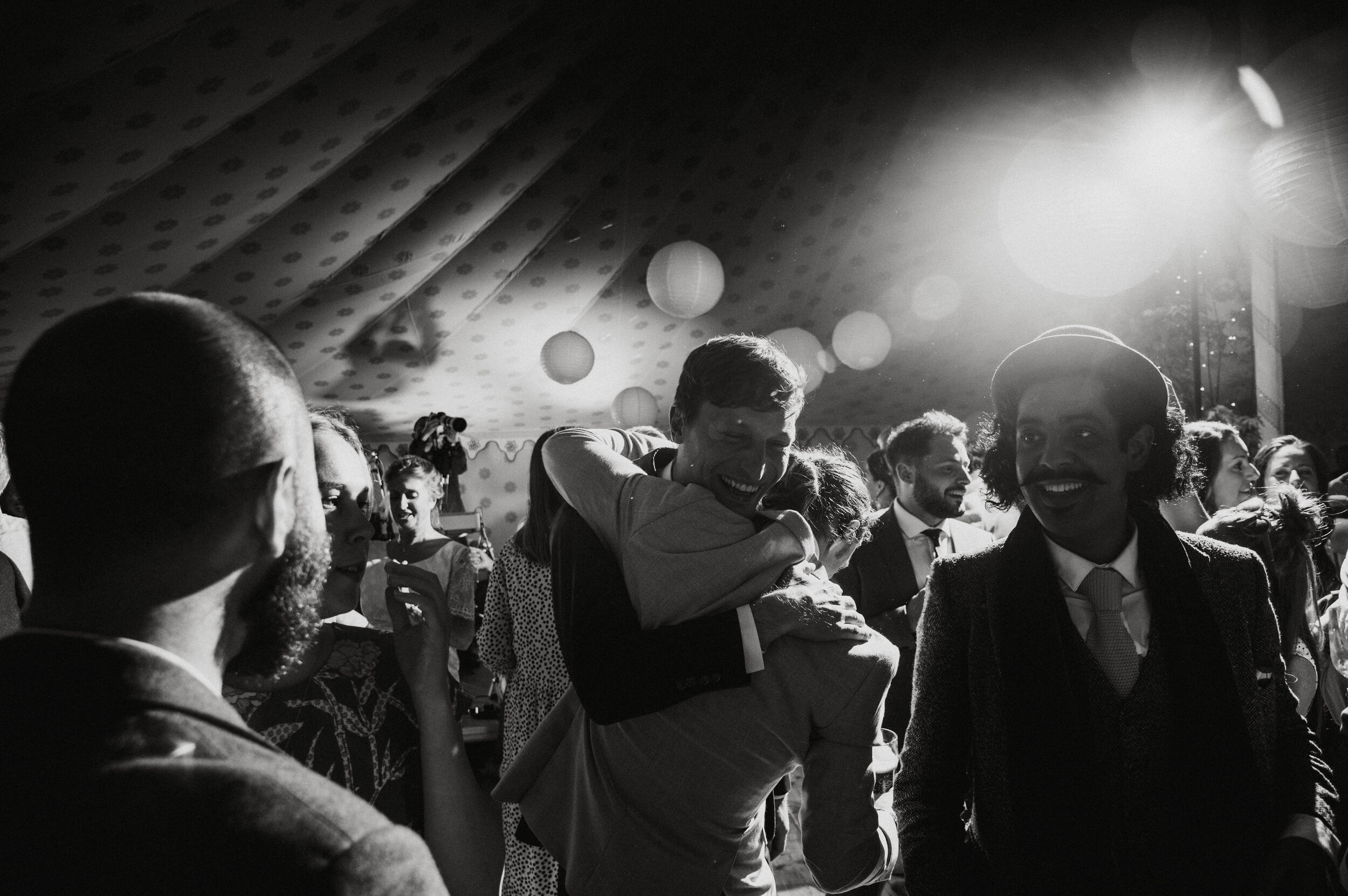 People dancing and socializing at a party or celebration with festive decorations, black and white photo.