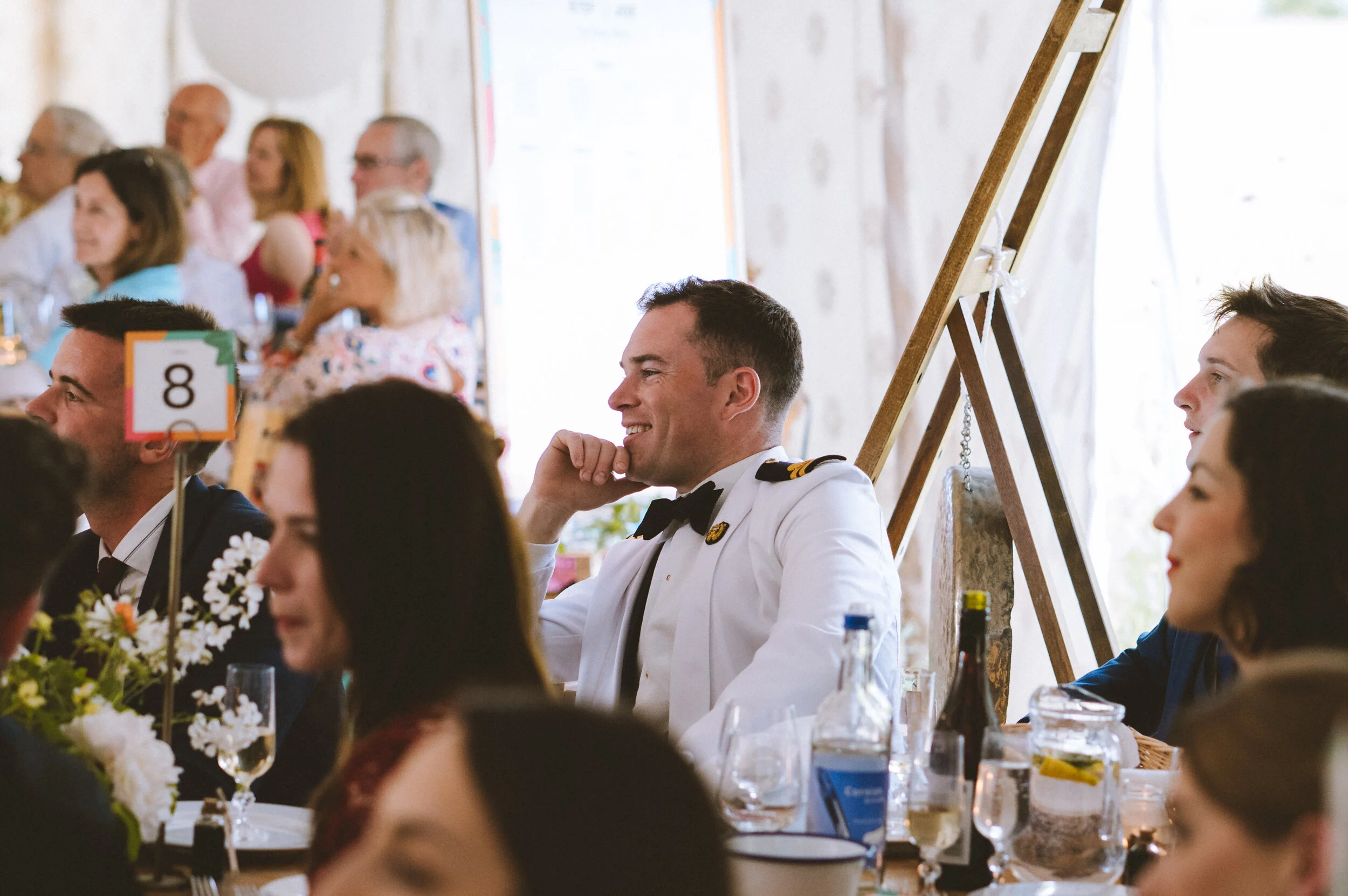 People dressed in formal attire, including a man in a military uniform, sitting at a banquet table during a celebration.
