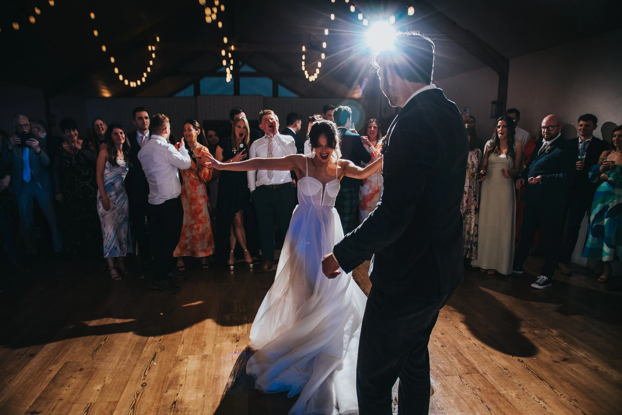 Bride and groom dancing at their wedding reception with guests watching and celebrating.