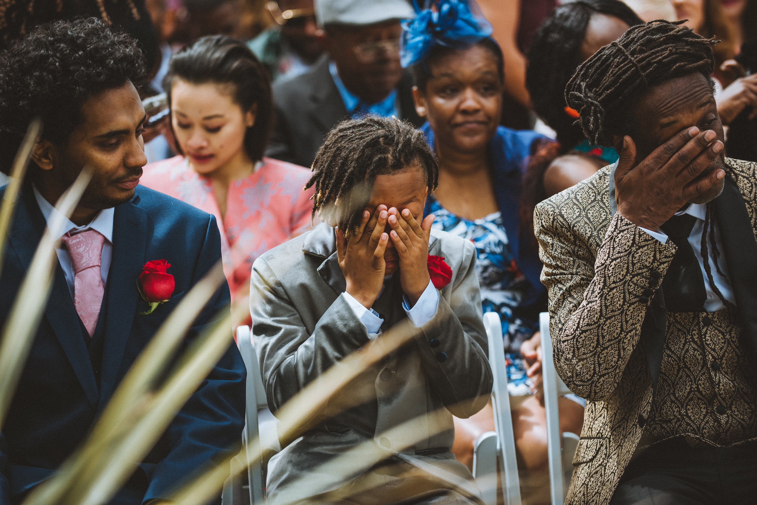 Guests at a wedding ceremony at Polhawn Fort in Cornwall, emotional expressions with boy crying. 