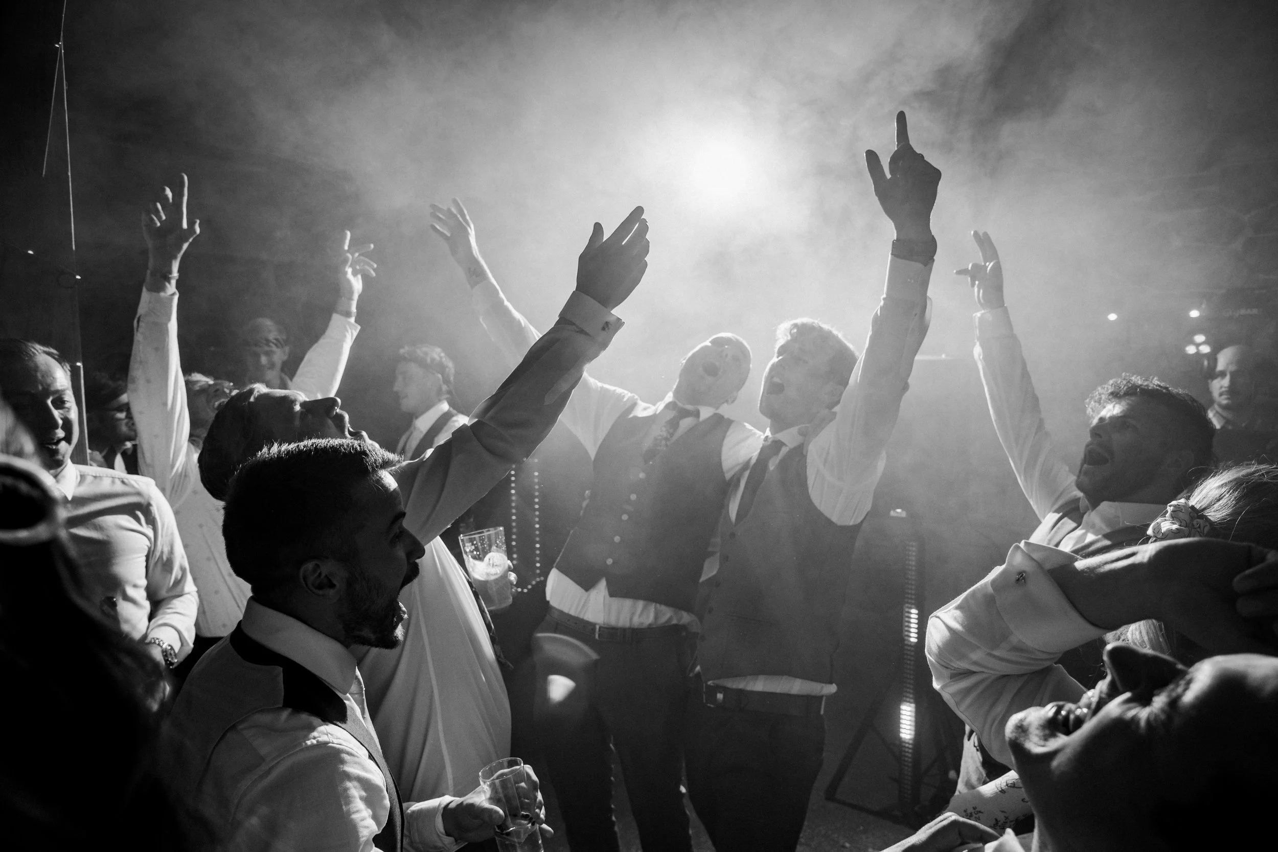 Group of people celebrating and cheering indoors, black and white photo.