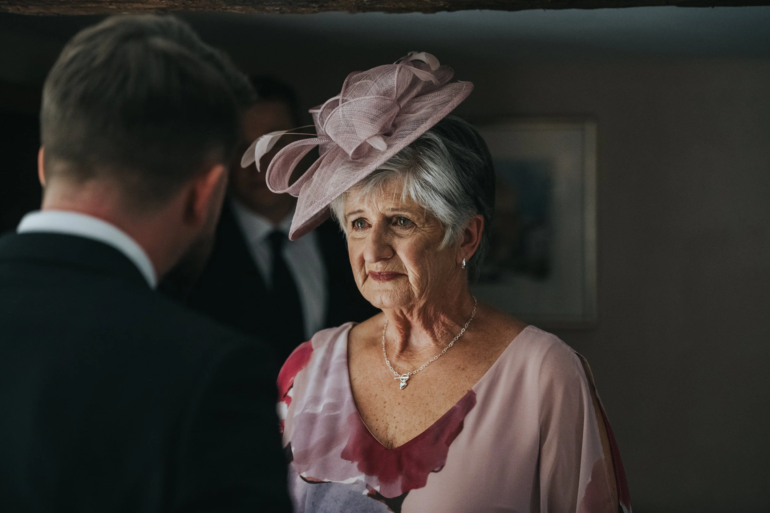 Elderly woman in floral dress and hat at event with man in suit.