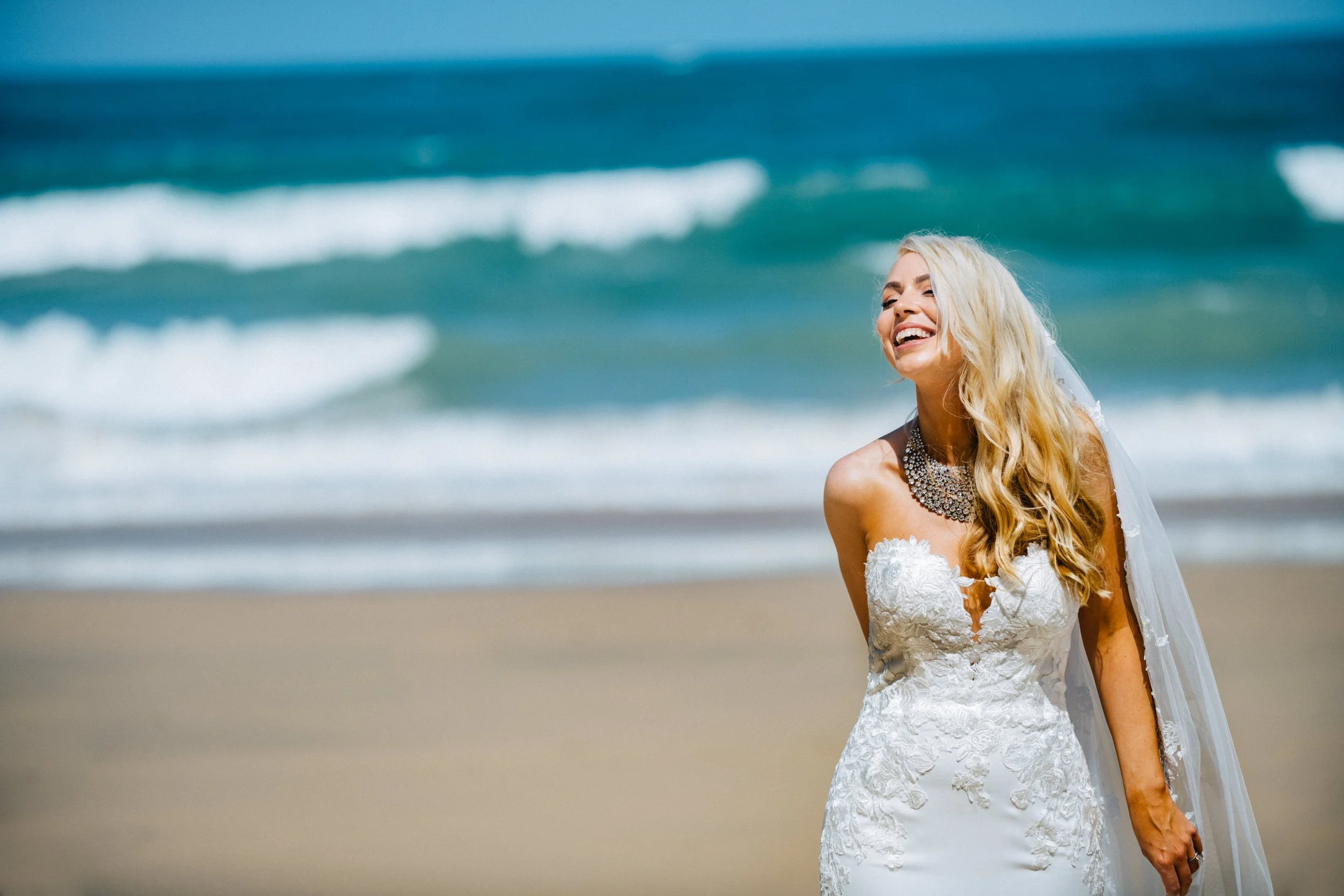 Smiling bride in lace wedding dress on Carbis Bay beach in Cornwall, captured by award-winning Cornwall wedding photographer, Mark Shaw. 