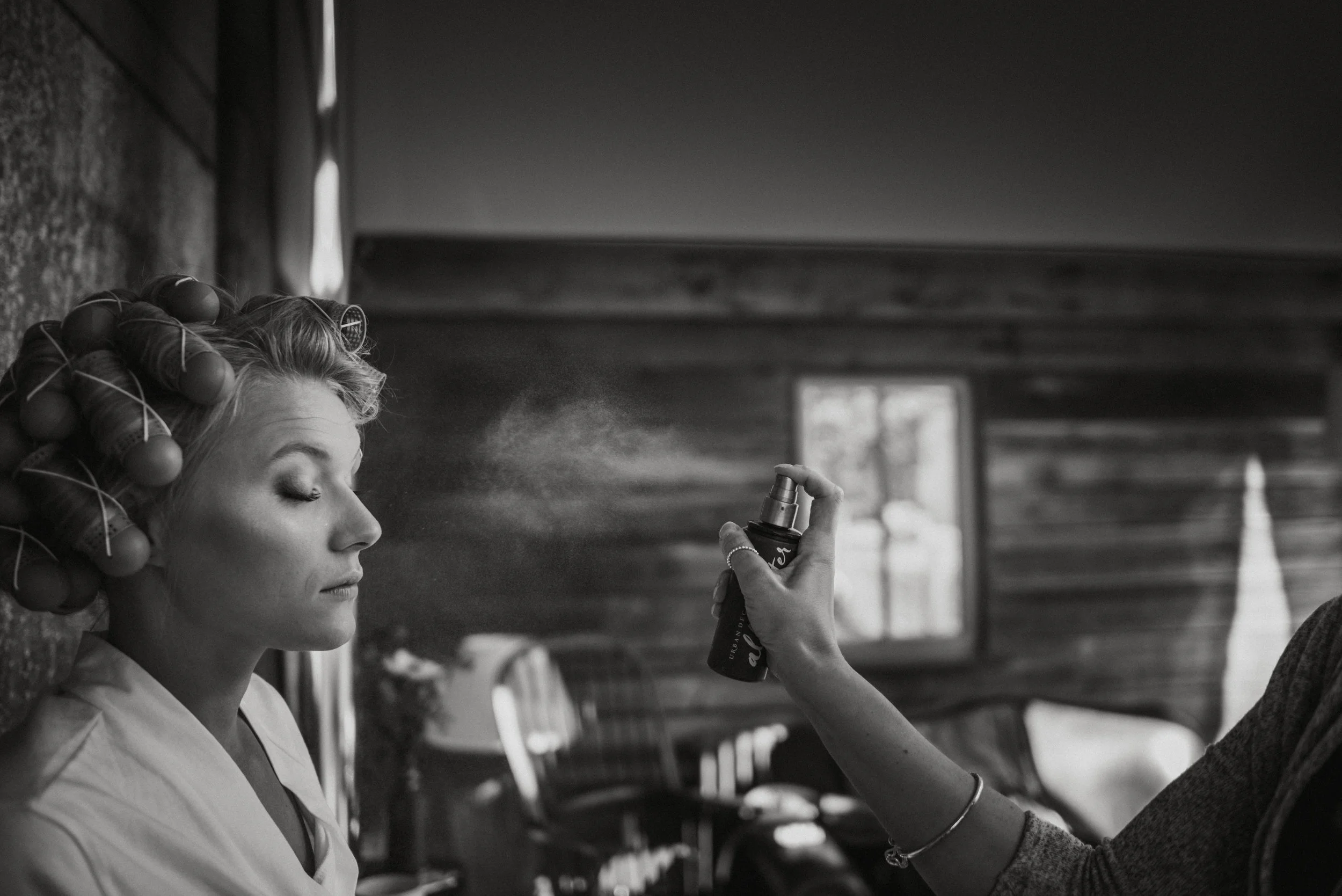 Woman with curlers having hair spray applied, captured by award-winning Cornwall wedding photographer, Mark Shaw. 