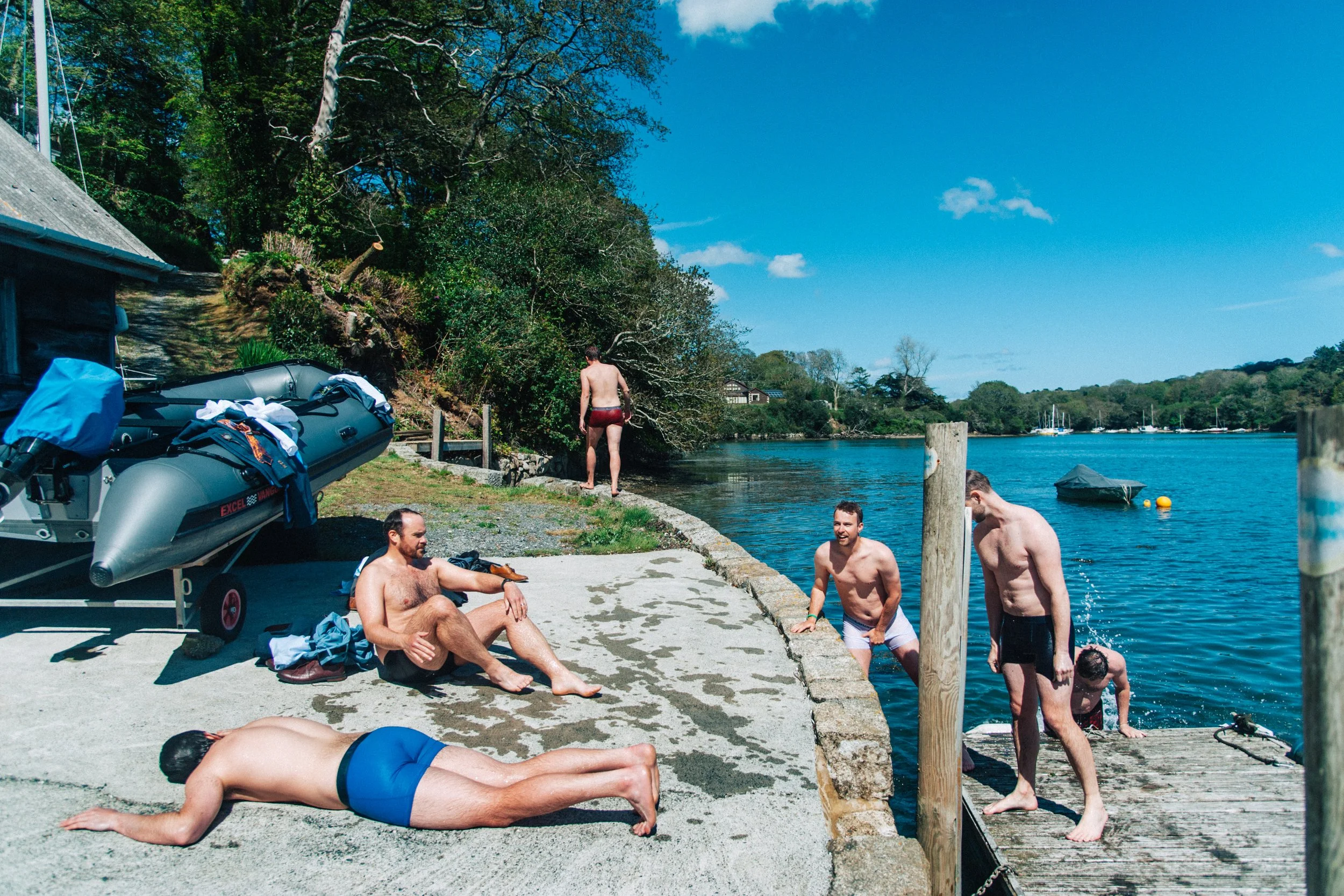 Groomsmen in swimwear, tired after swimming in the sea on the Helford River, Cornwall. 