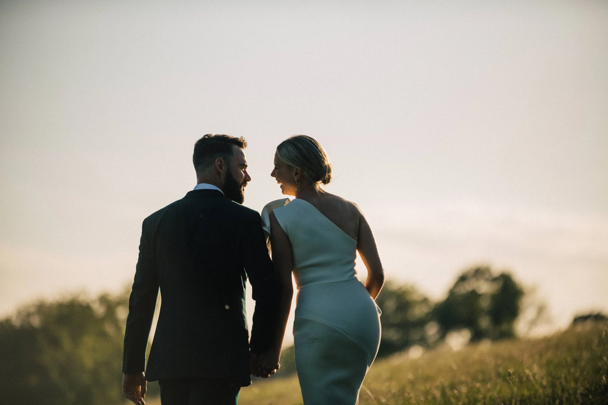 Bride and groom holding hands walking during sunset