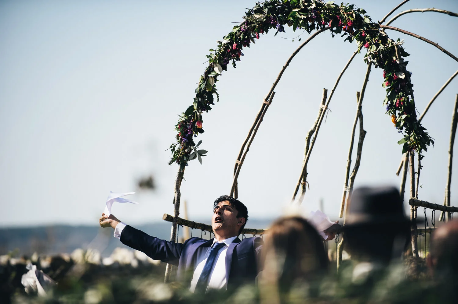 Man in suit performing outdoors under a floral arch