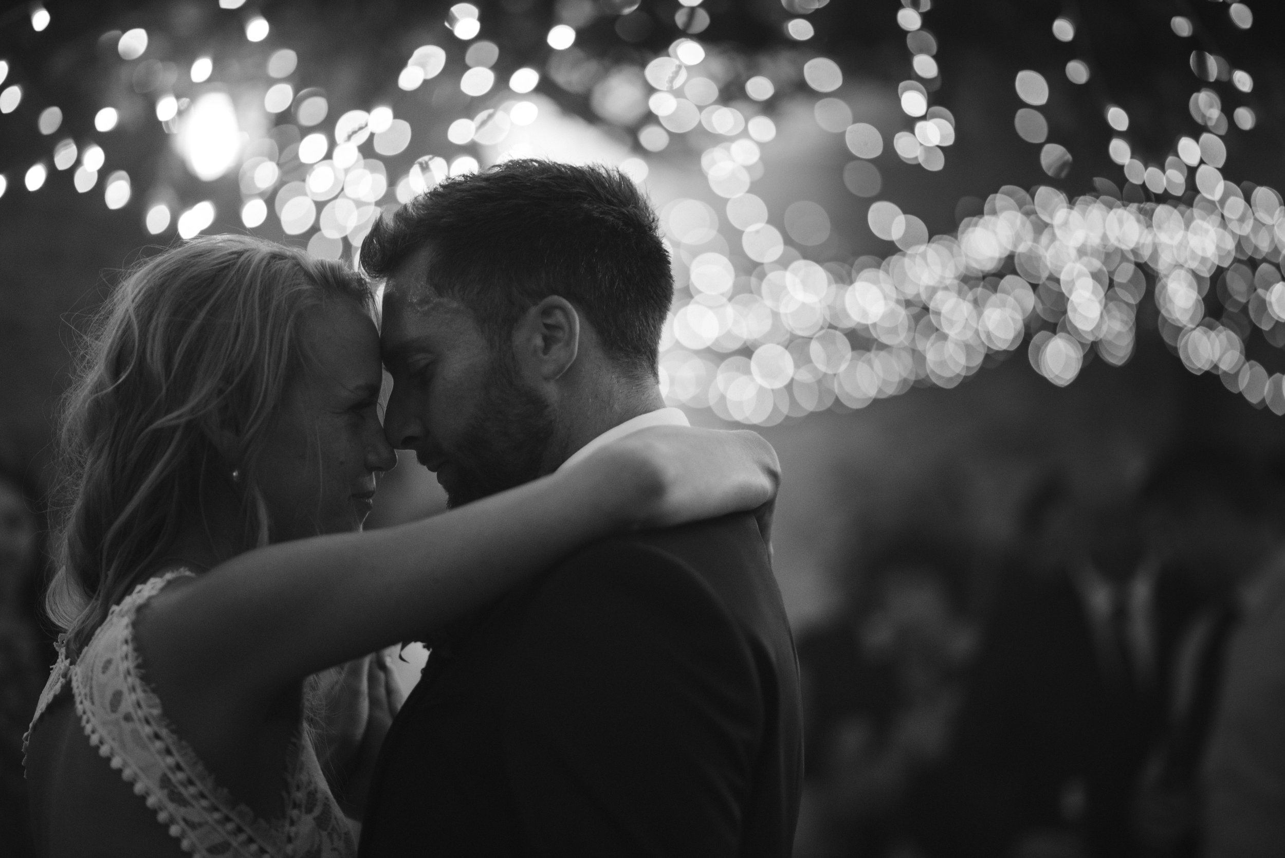 Couple dancing under string lights at an event