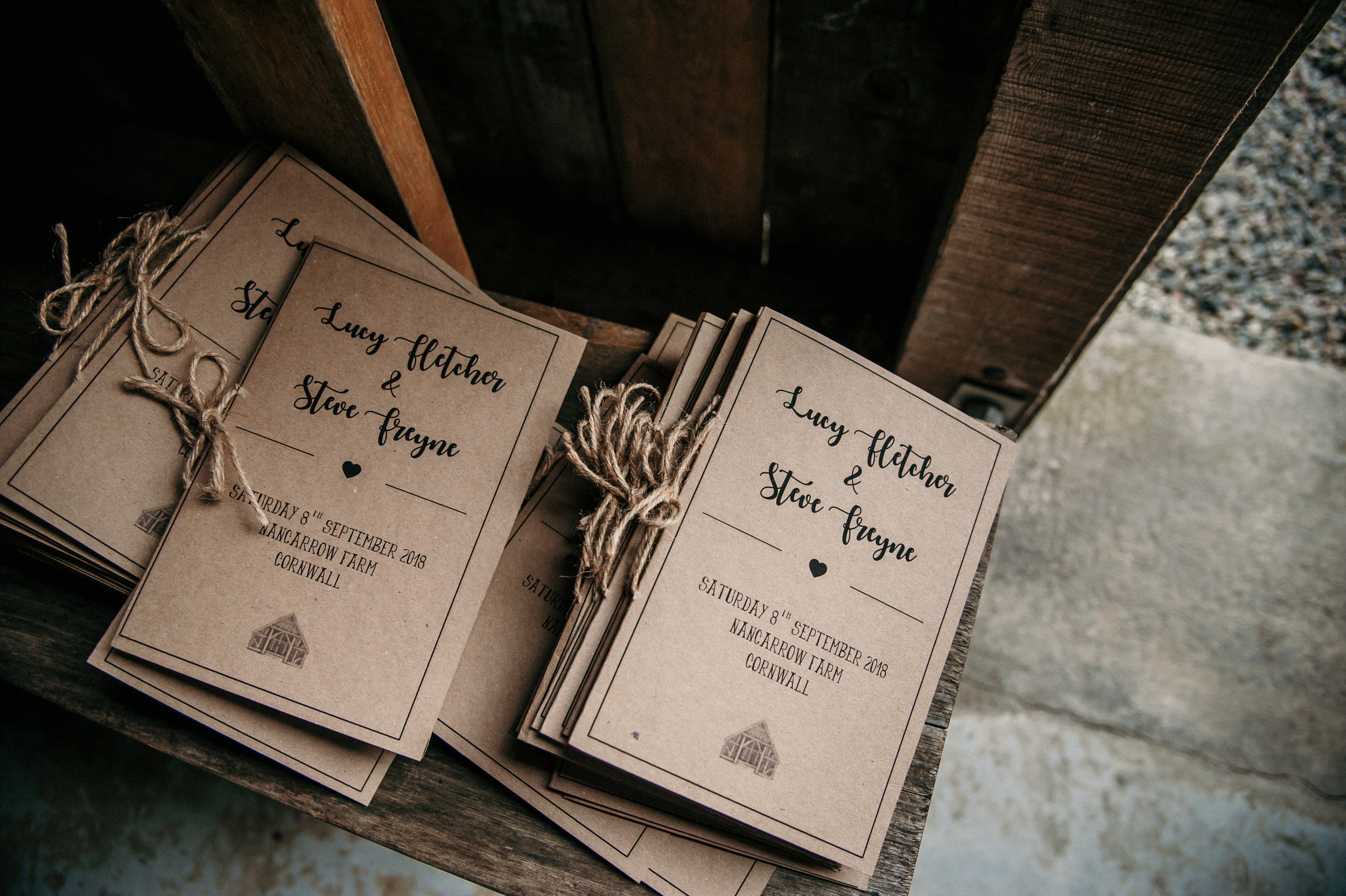 Stacks of wedding invitations tied with twine on a rustic wooden surface.