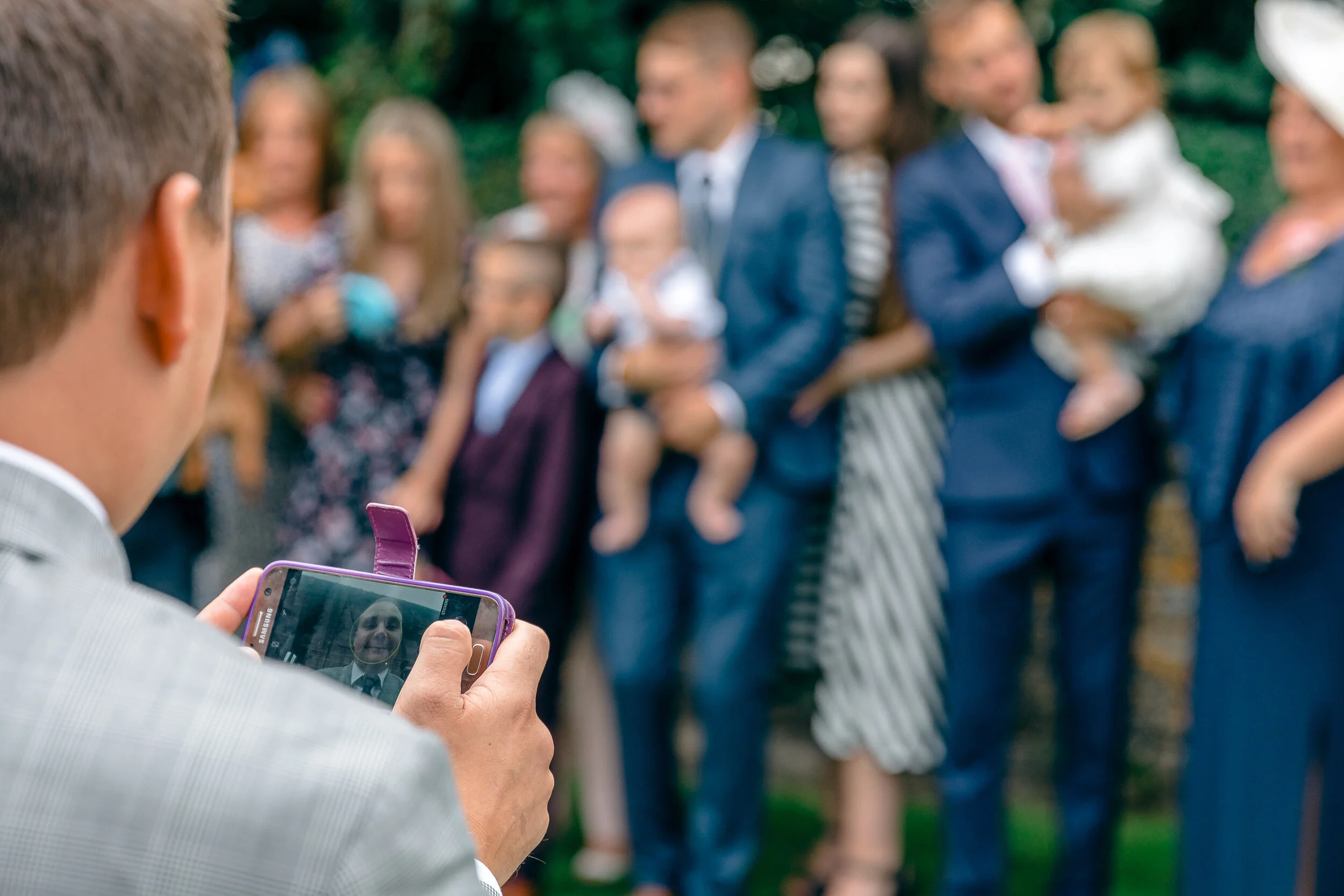 Person taking a photo of a group of people at an outdoor event, with the camera screen showing their faces.