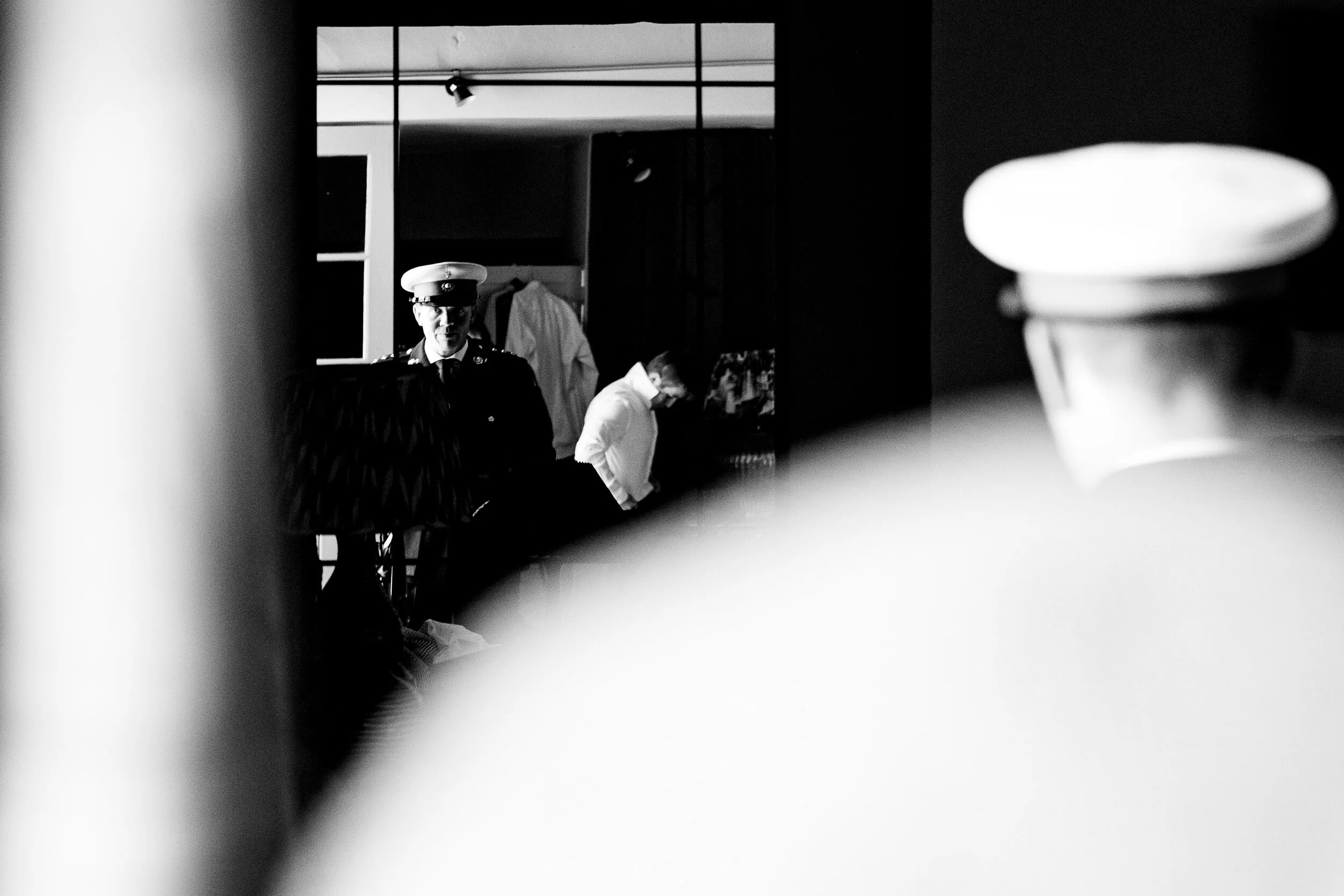 Black and white photo of a police officer and two men in a room, viewed through an obscured foreground.