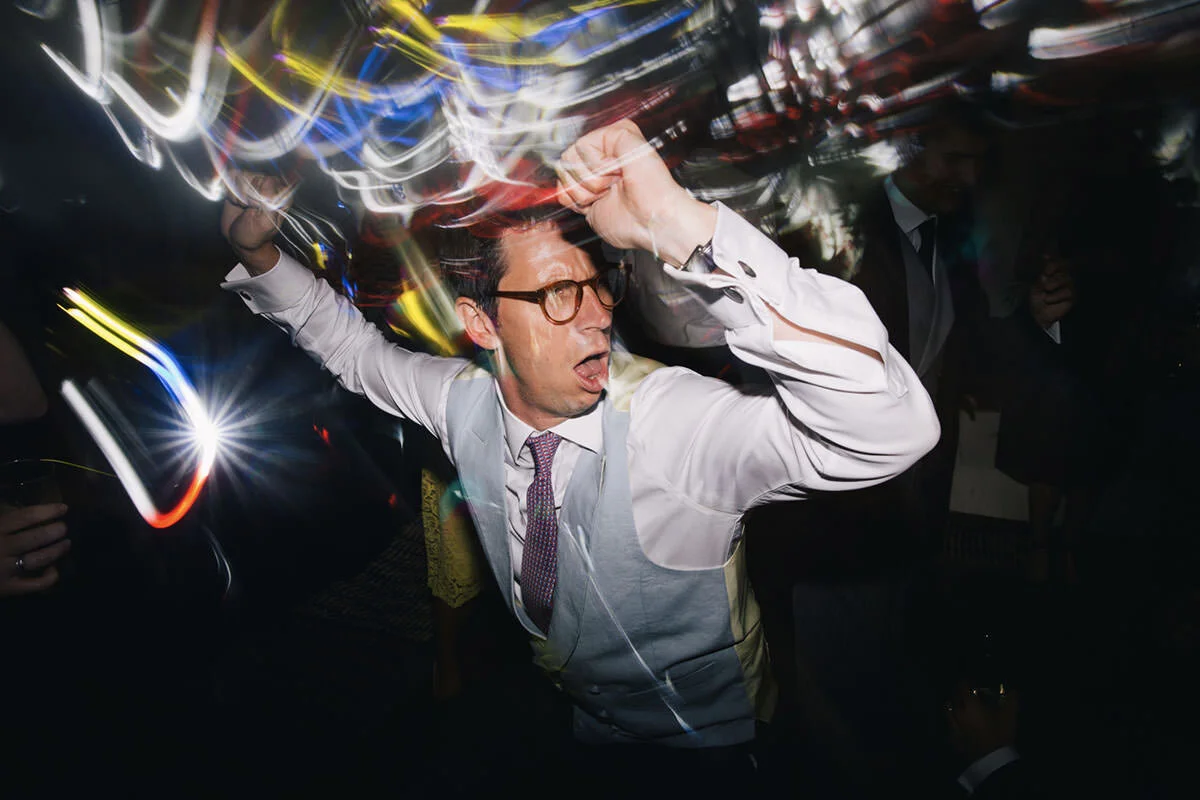 A man dancing at a party with colorful lights and motion blur.