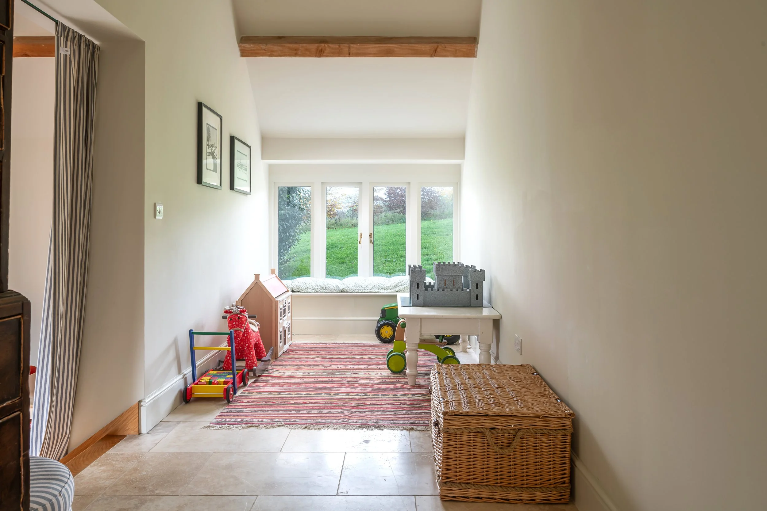 Bright children's playroom with toys, a striped rug, a window seat, and decorated wall art.