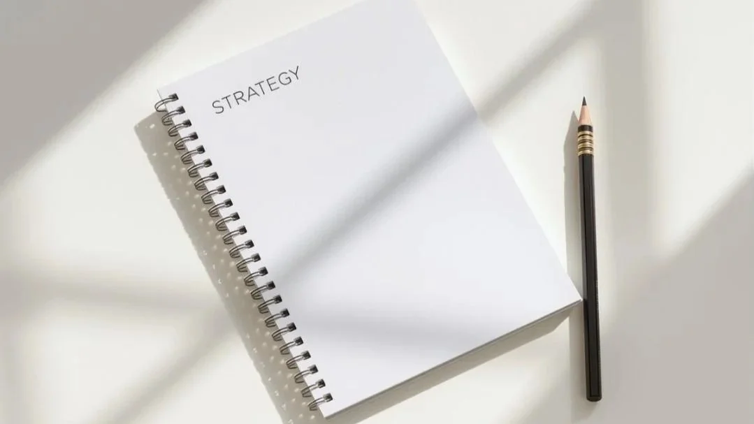 Cahier ouvert avec l'inscription 'Strategy' en haut et un crayon noir sur une surface blanche