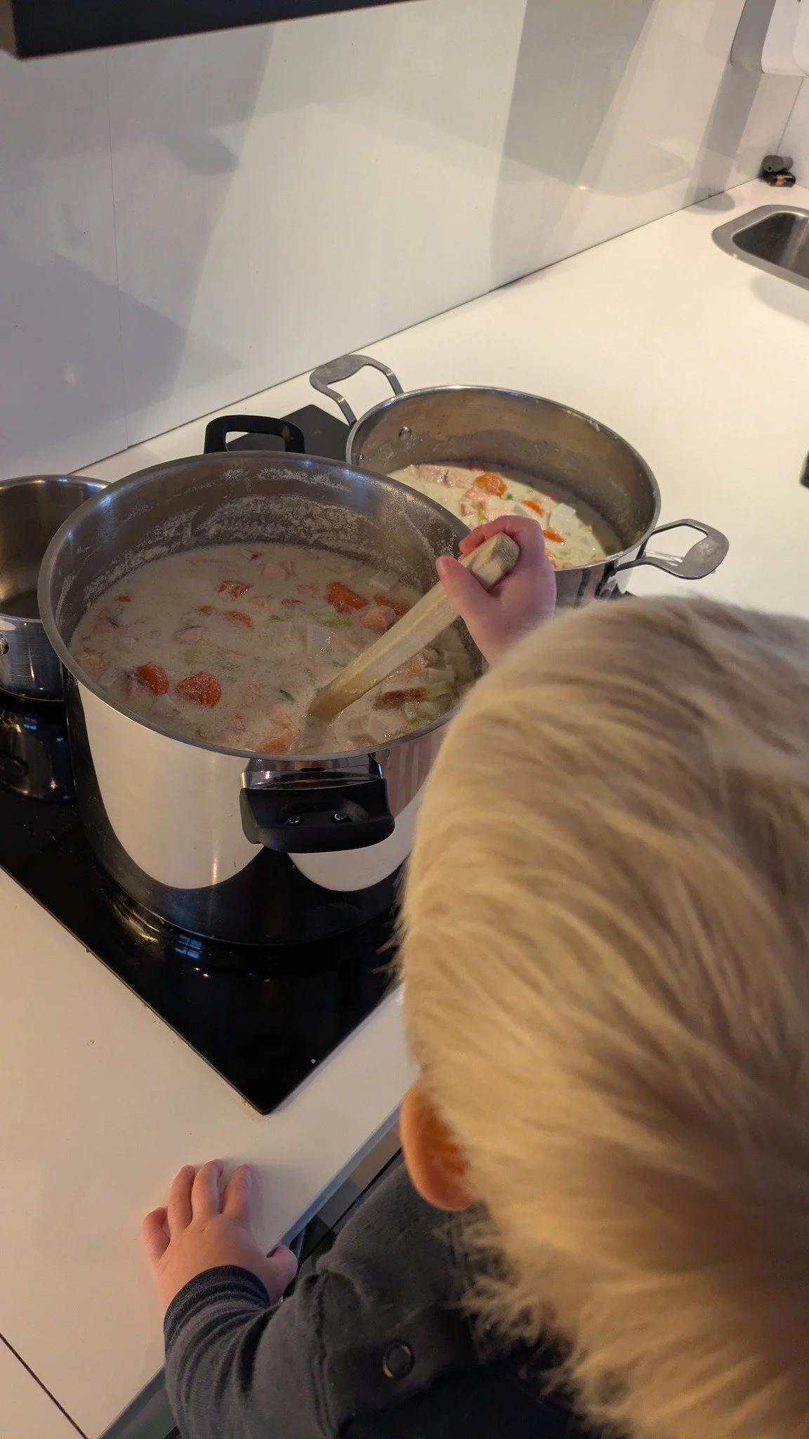 Et barn rører i en gryte som står på komfyren